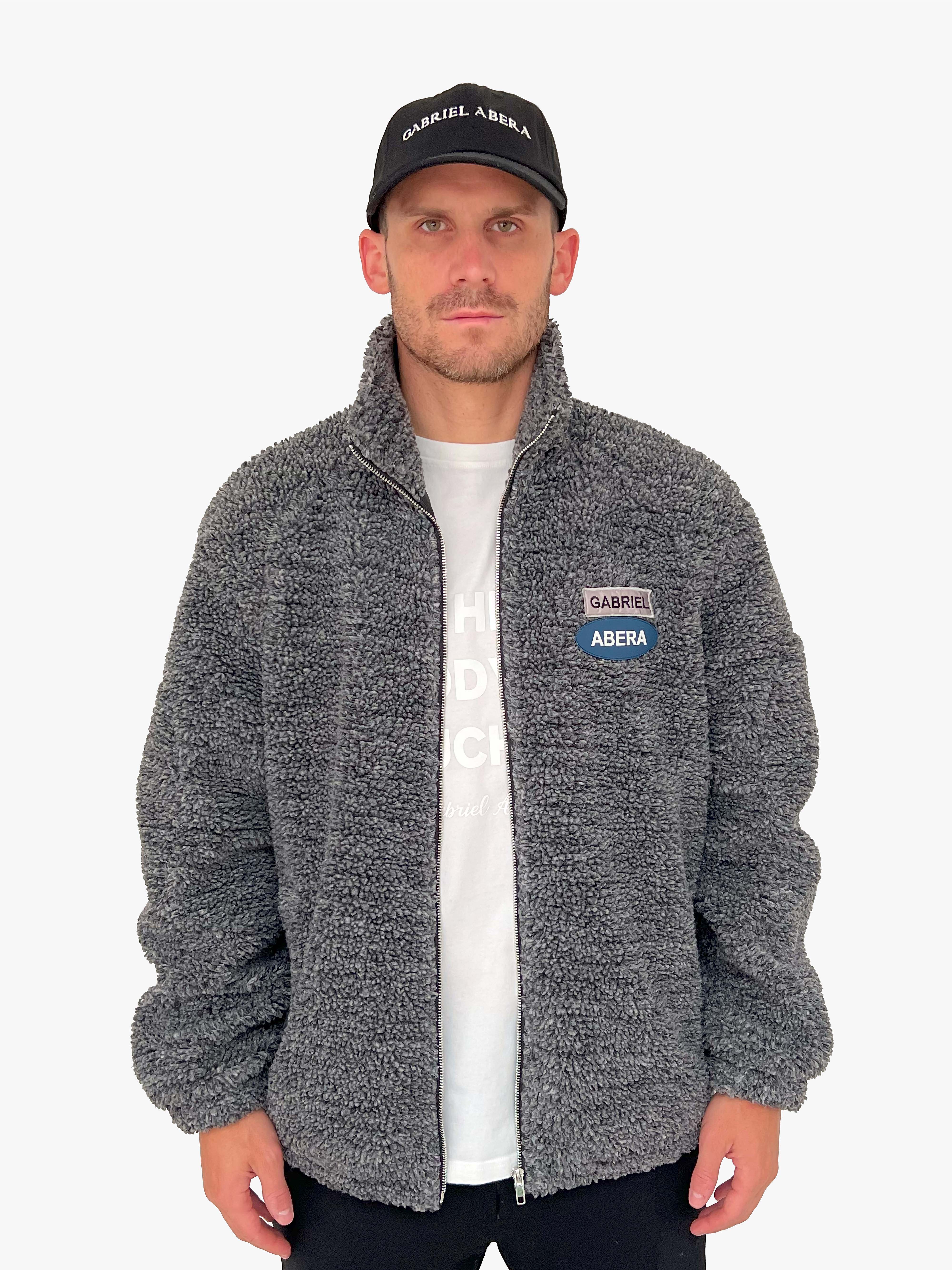 Male model wearing a black fleece jacket with green yelgrey blue brand patches