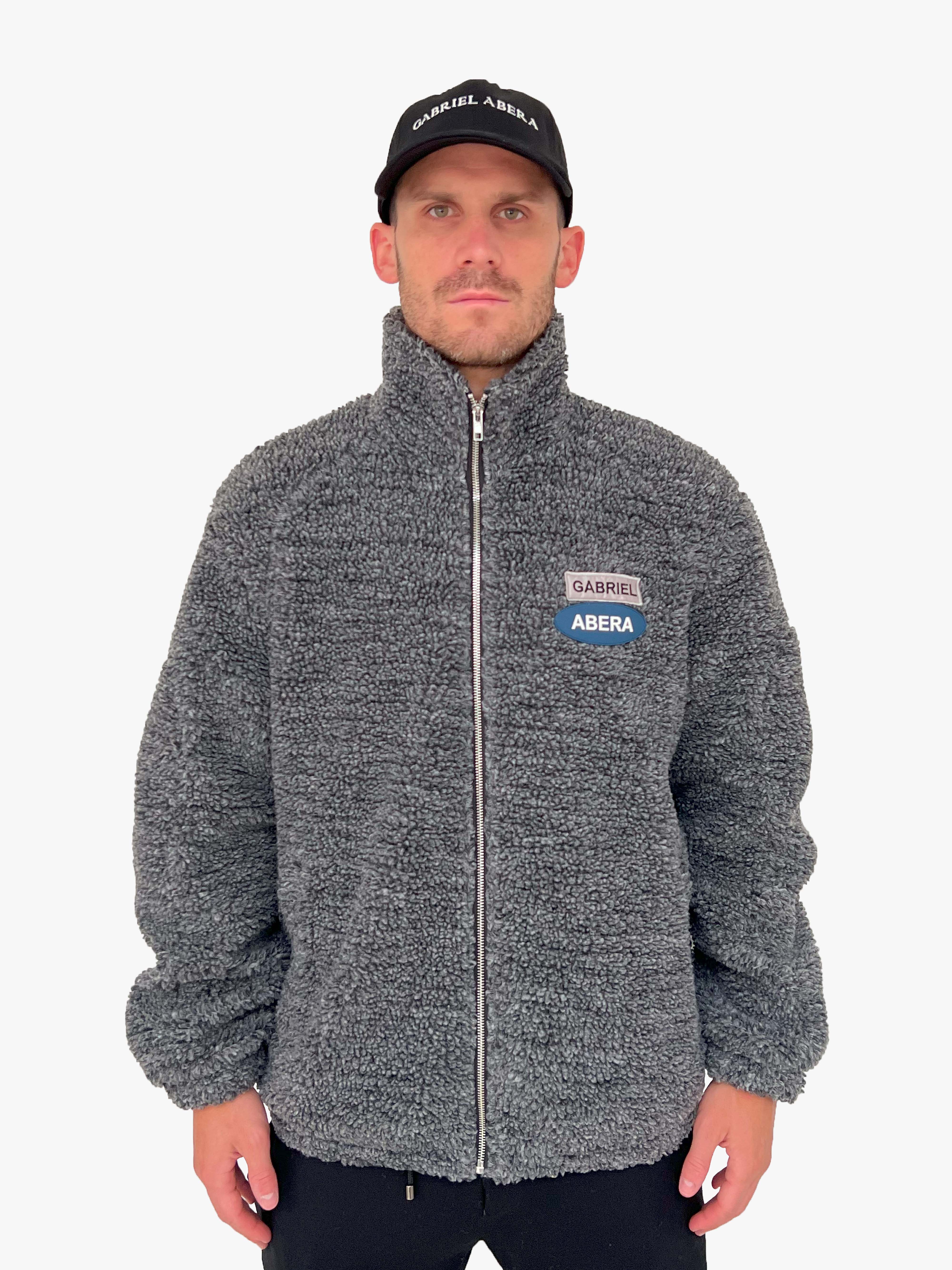 Male model wearing a black fleece jacket with grey and blue brand patches