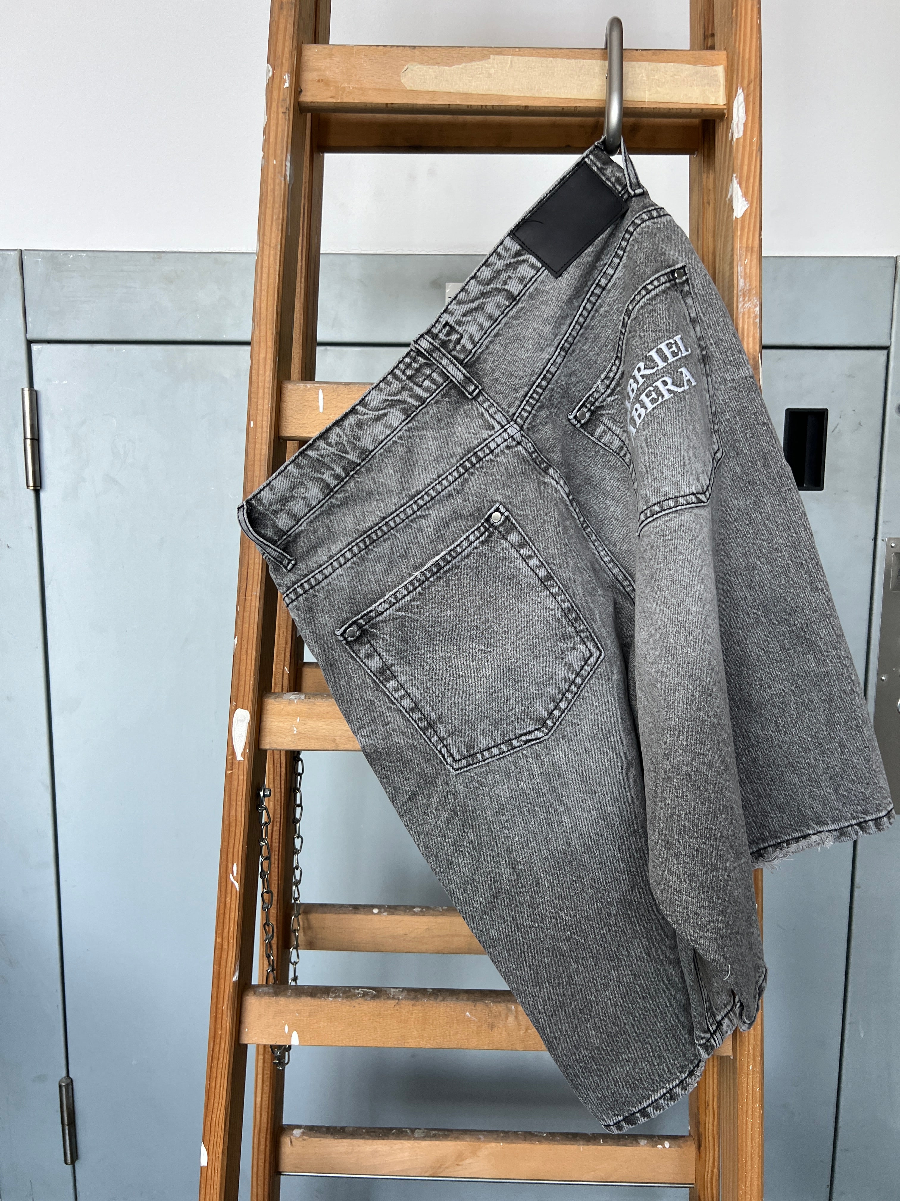 Back pocket embroidery detail on Gabriel Abera Rhinestones Denim Jorts hanging on ladder