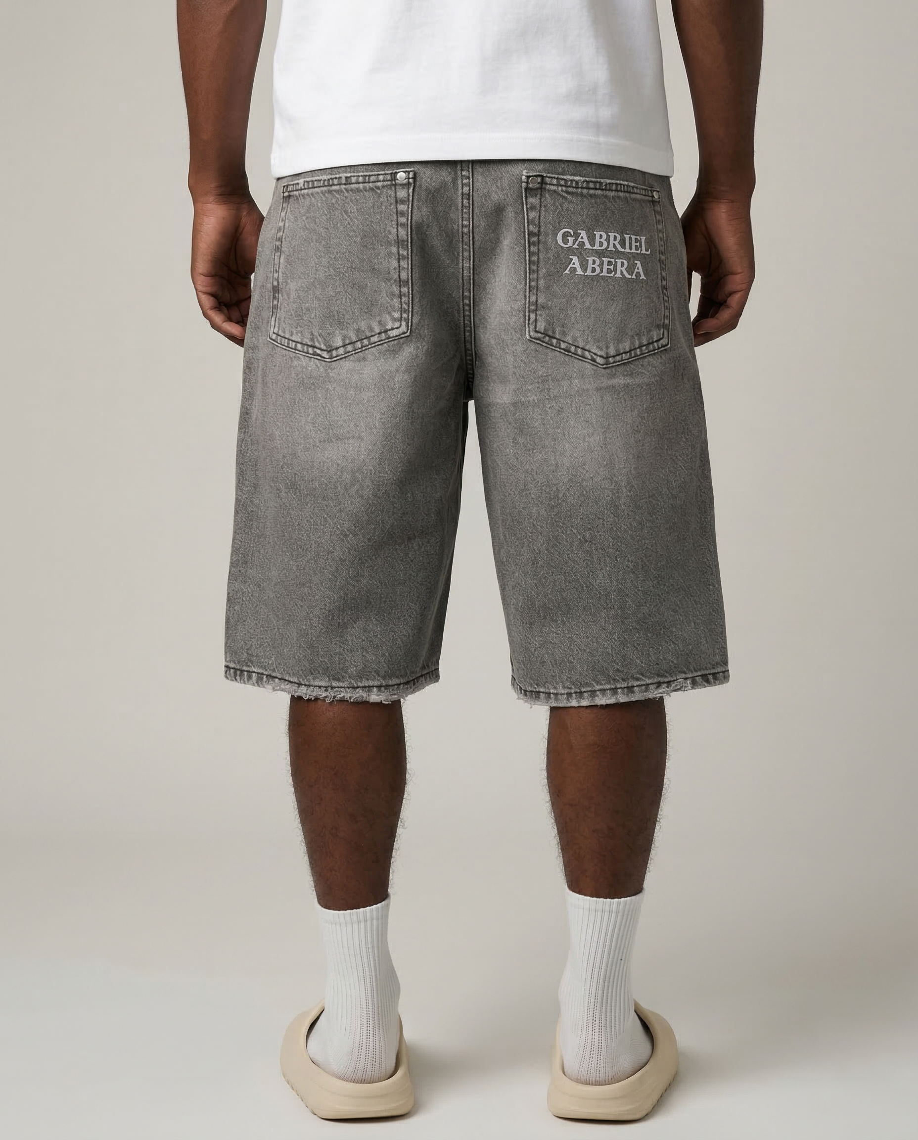 Back view of model wearing Gabriel Abera Splattered Denim Shorts, cropped at waist