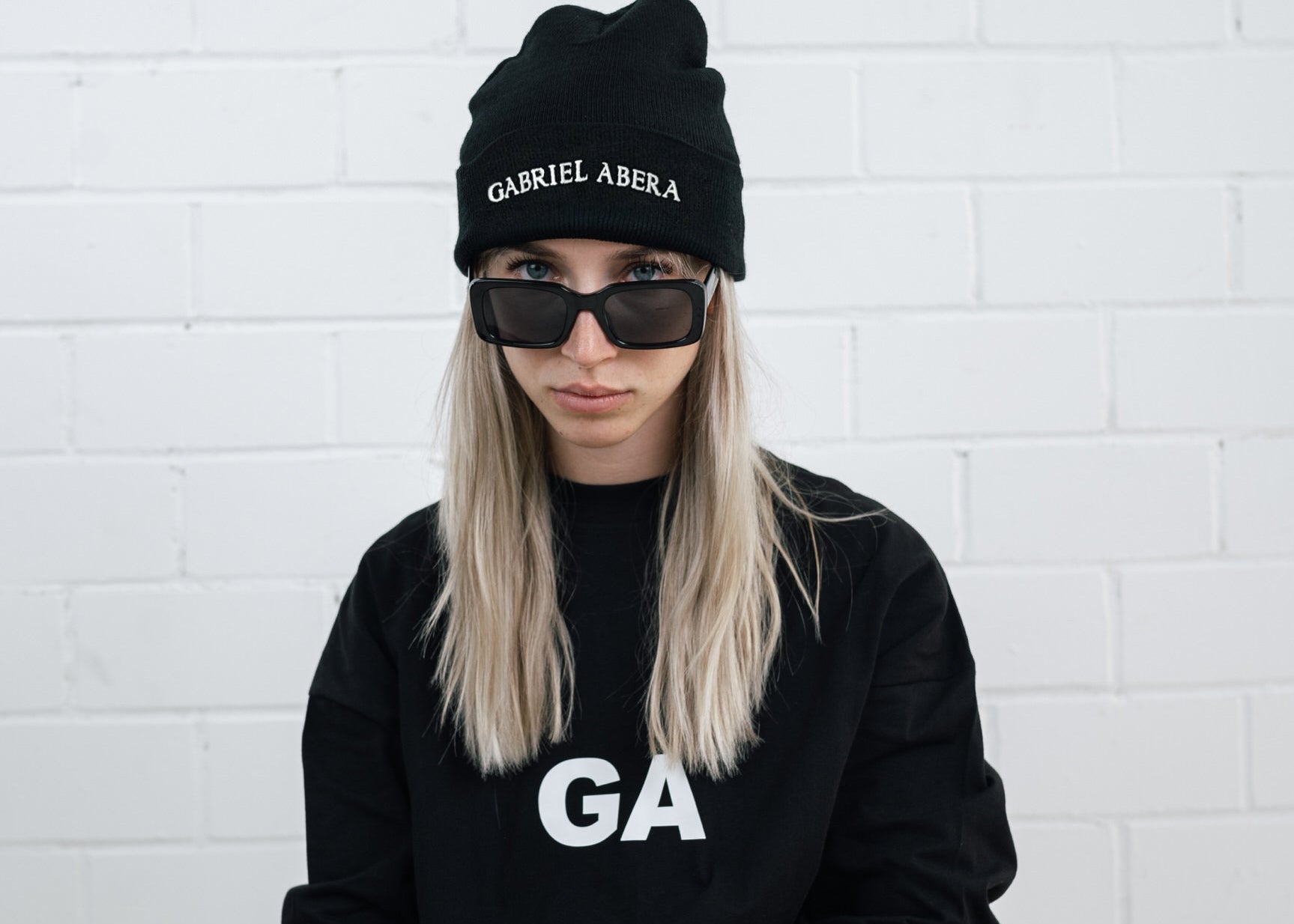 Female model wearing a Black beanie with brand name embroidery