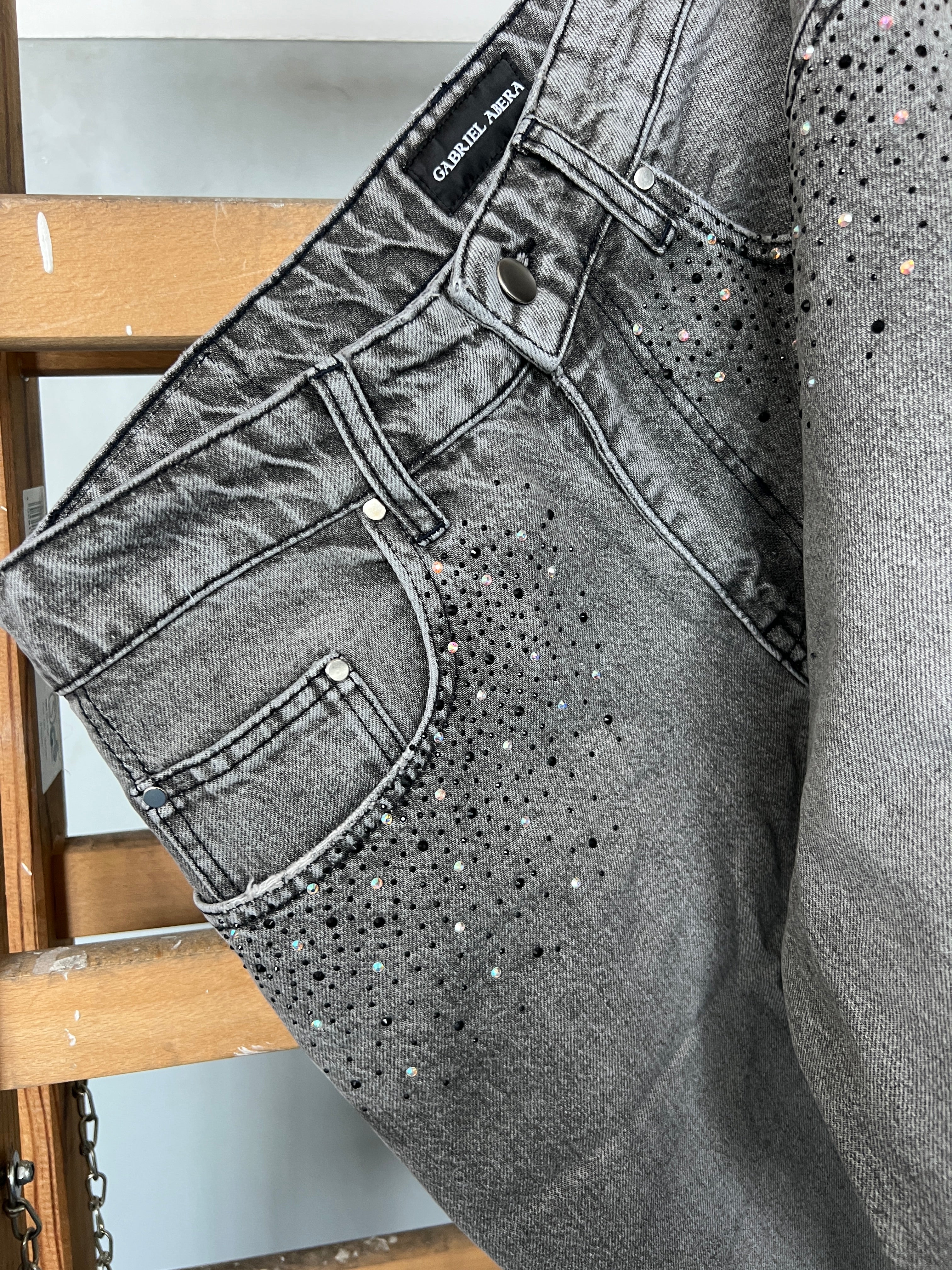 Close-up of rhinestone embellishment on Gabriel Abera Rhinestones Denim Jorts hanging on ladder