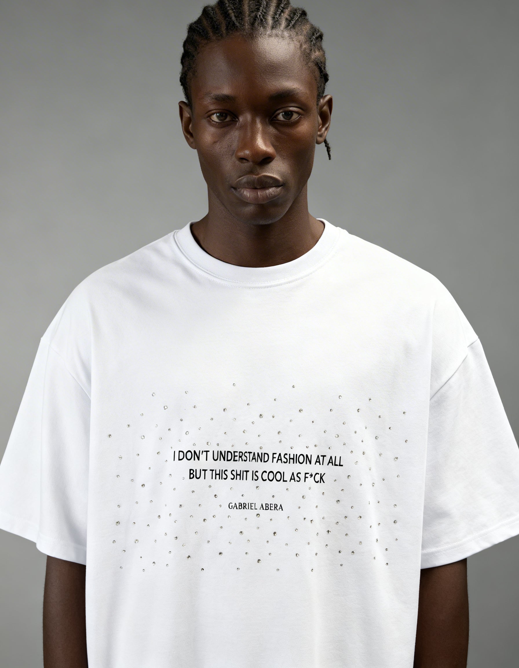 Close-up of rhinestone embellishments and statement text print on white oversized T-shirt by GABRIEL ABERA.