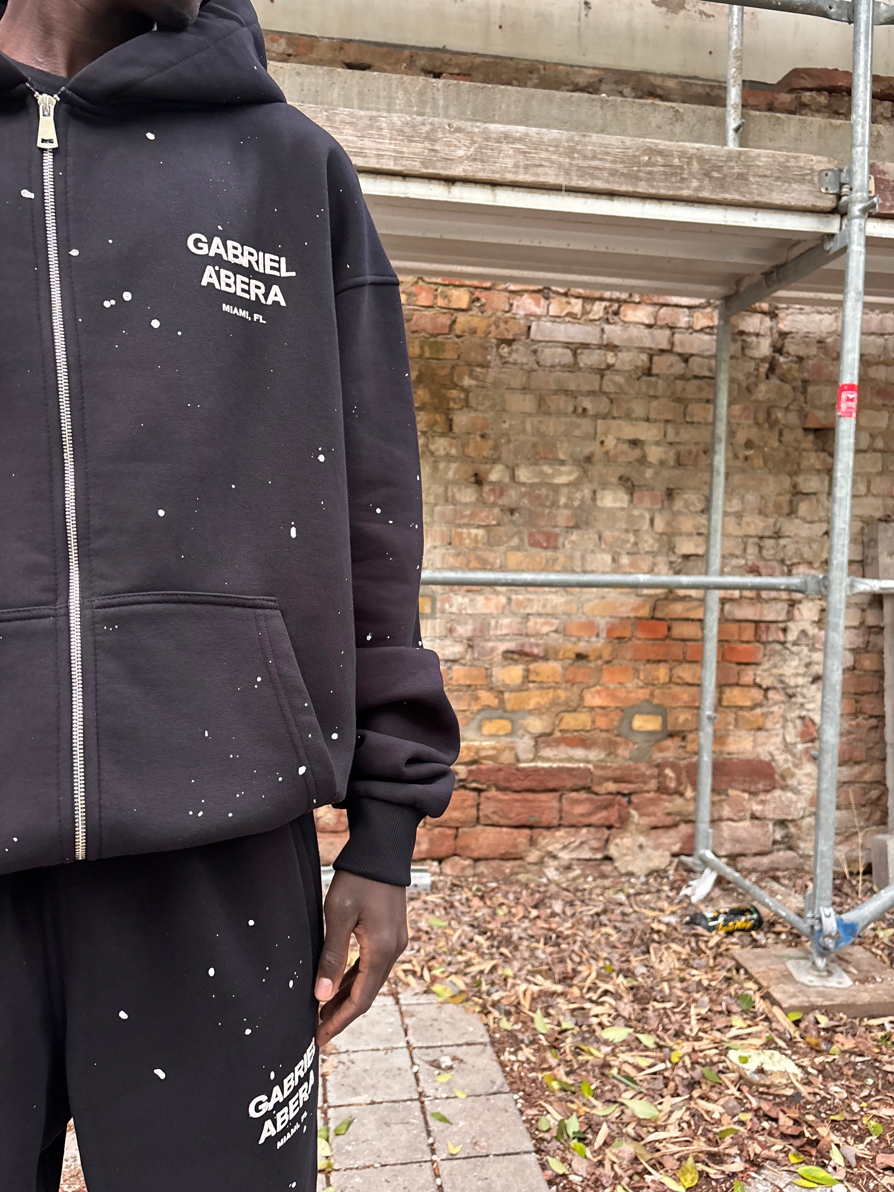 Detailaufnahme Kapuze & Reißverschluss des GABRIEL ABERA Splattered Puff Zip Hoodie mit Splatter-Effekt.