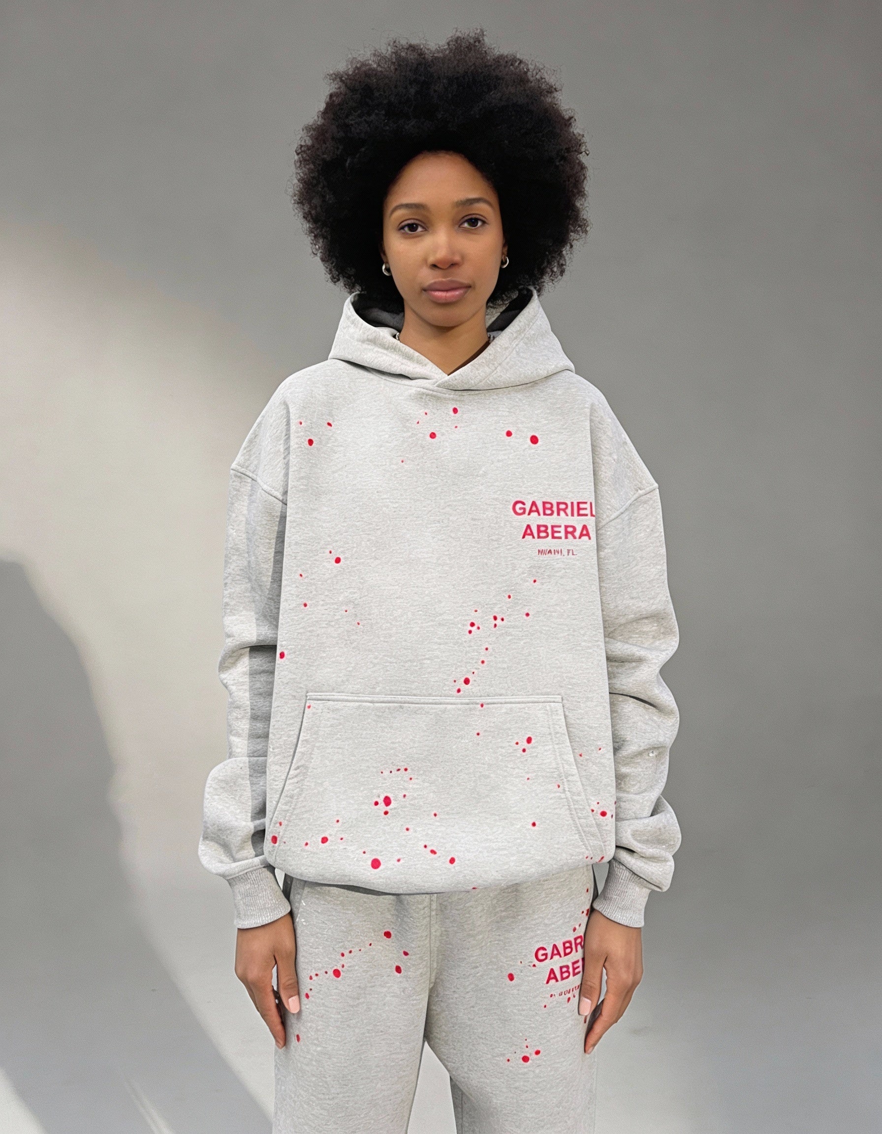 Front view female model with Grey Splattered Puff Hoodie with red hand-painted details by Gabriel Abera, puff print, and oversized streetwear design.