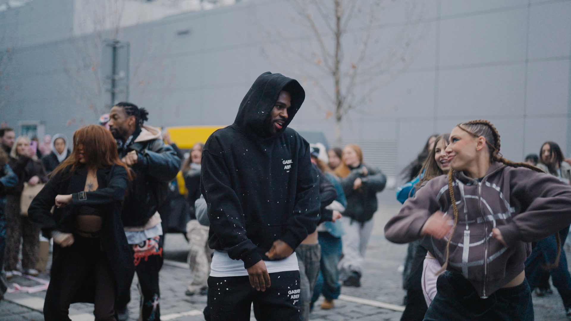 Full body shot of Jason Derulo wearing GABRIEL ABERA paint splattered tracksuit with black hoodie and pants in streetwear style while dancing in Prague.