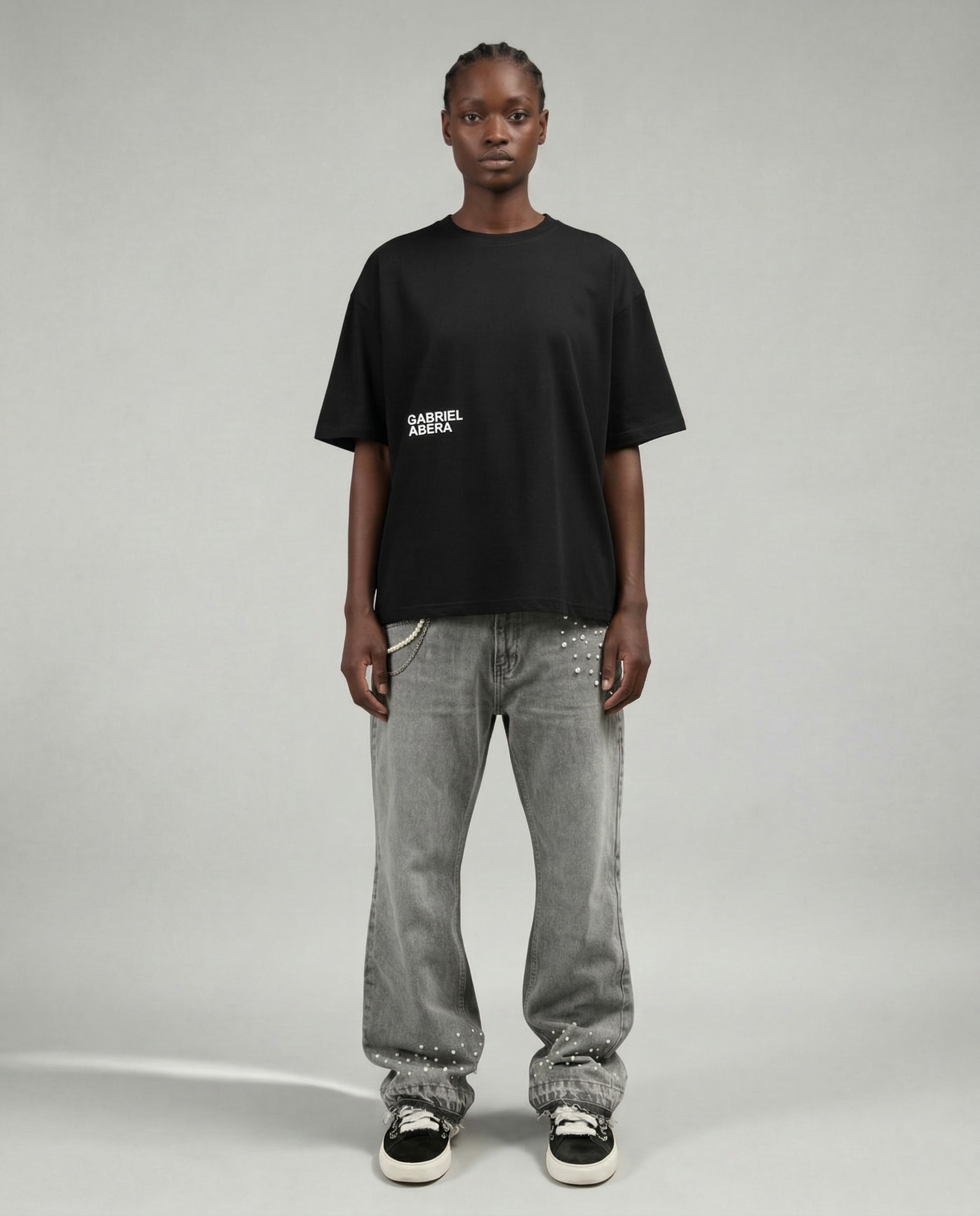 Full outfit shot of black boxy streetwear T-shirt by GABRIEL ABERA styled with grey denim jeans.