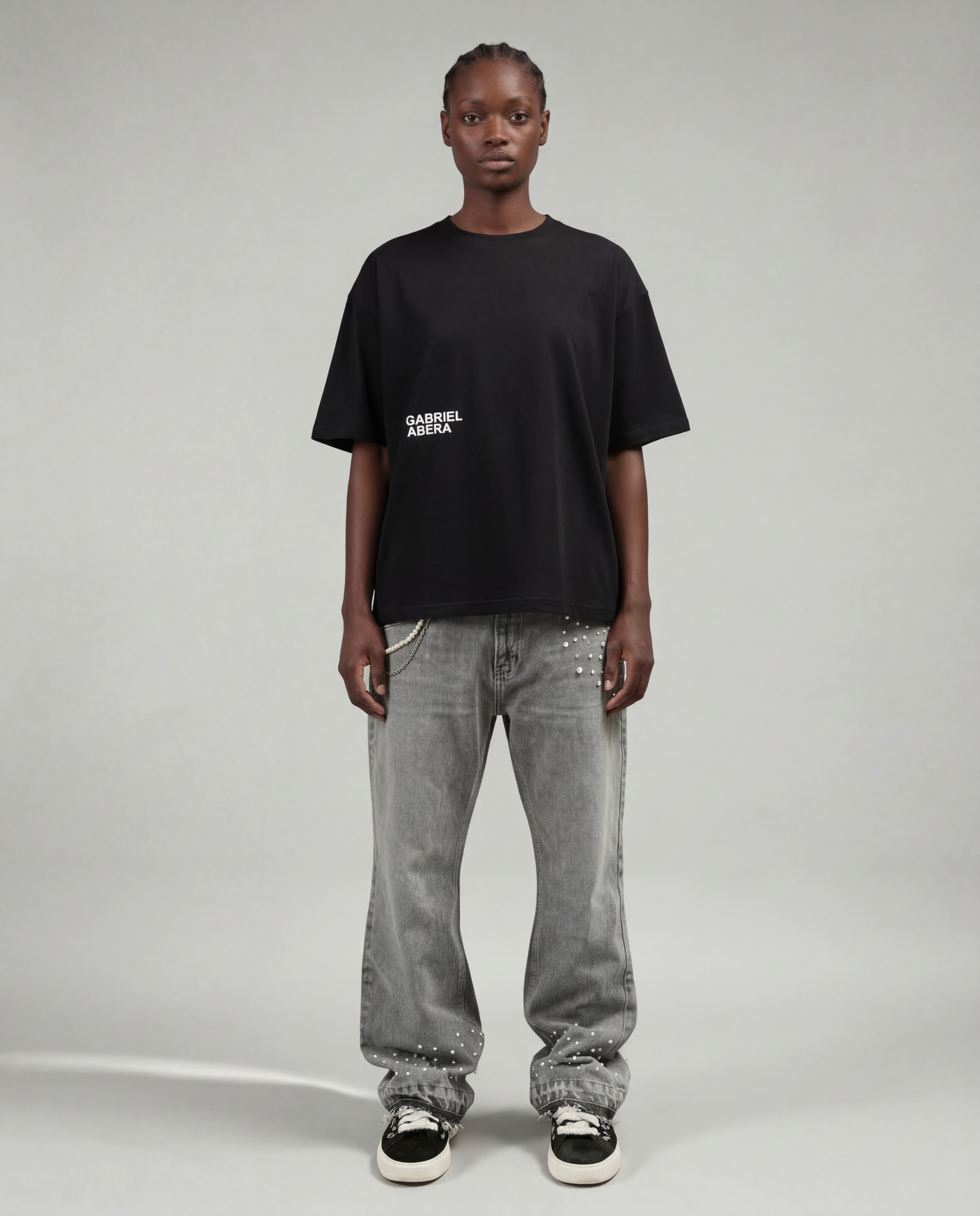 Full outfit shot of grey rhinestone denim jeans by GABRIEL ABERA featuring loose fit silhouette and rhinestone details on front pocket and lower leg.