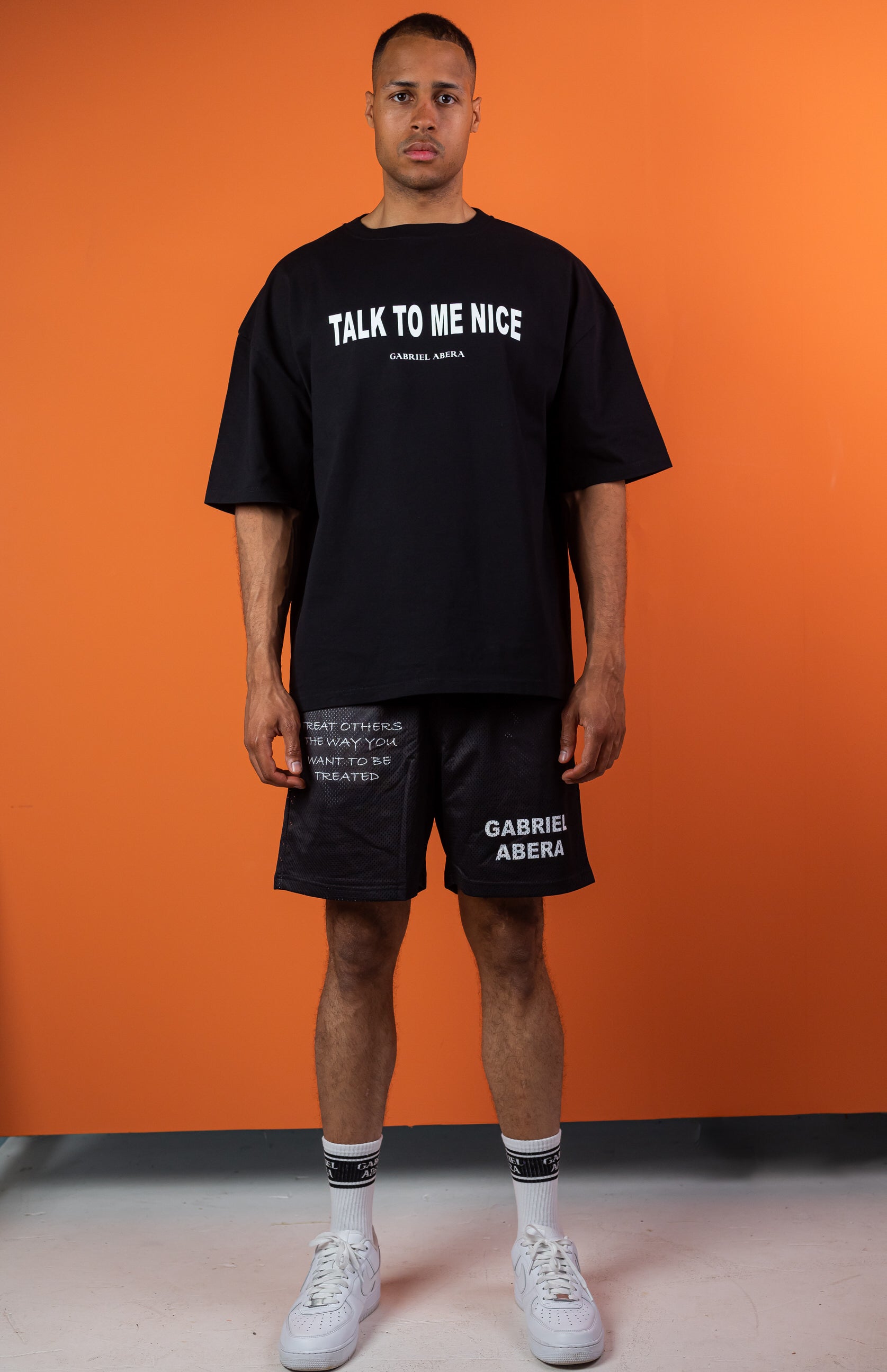 Male model wearing a Black oversize tshirt with white talk to me nice design on the front