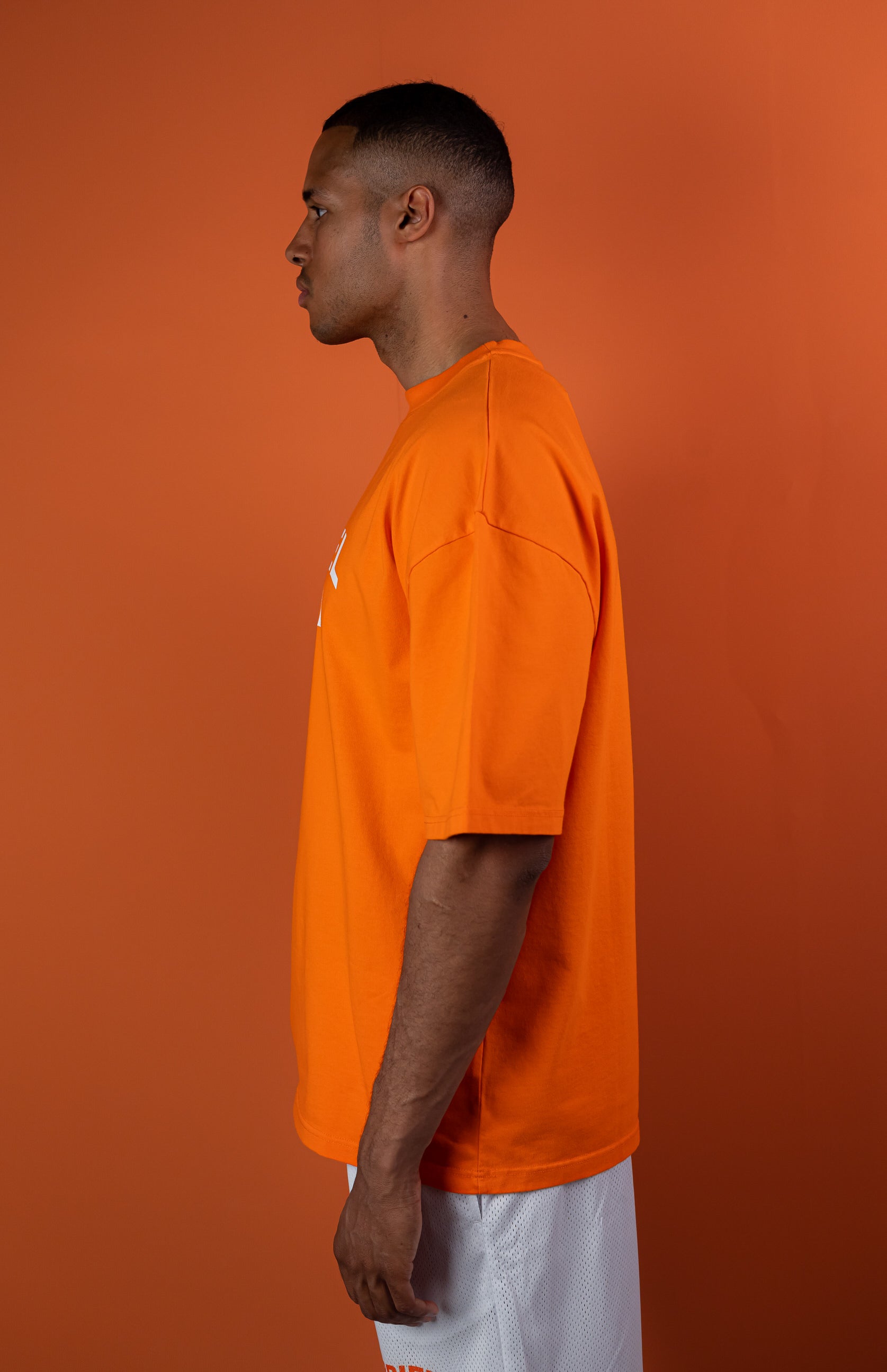 Model wearing a orange oversize tshirt with whitewavy brand name design