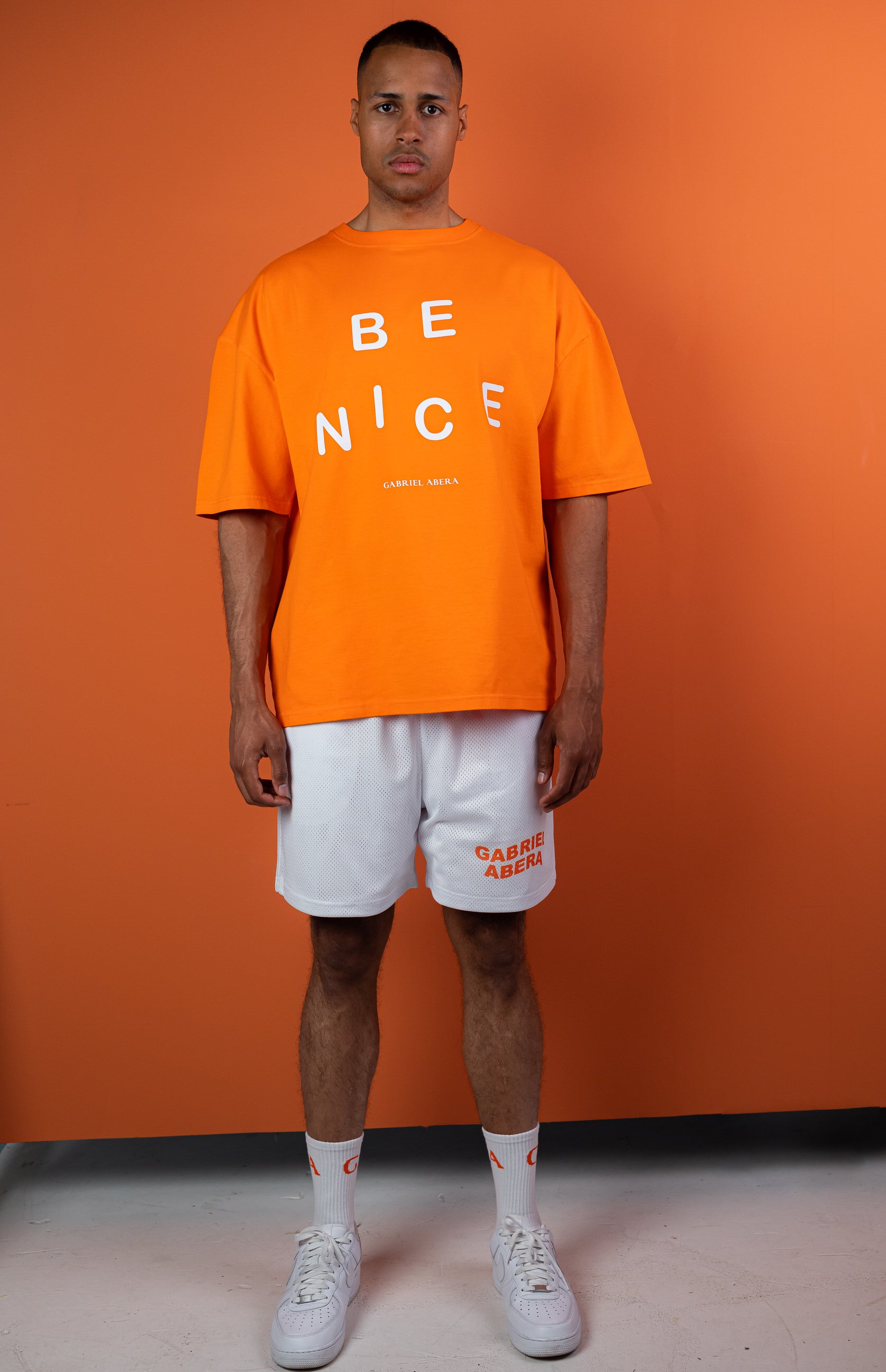 Male Model wearing Orange oversize tshirt with "be nice" print on the front