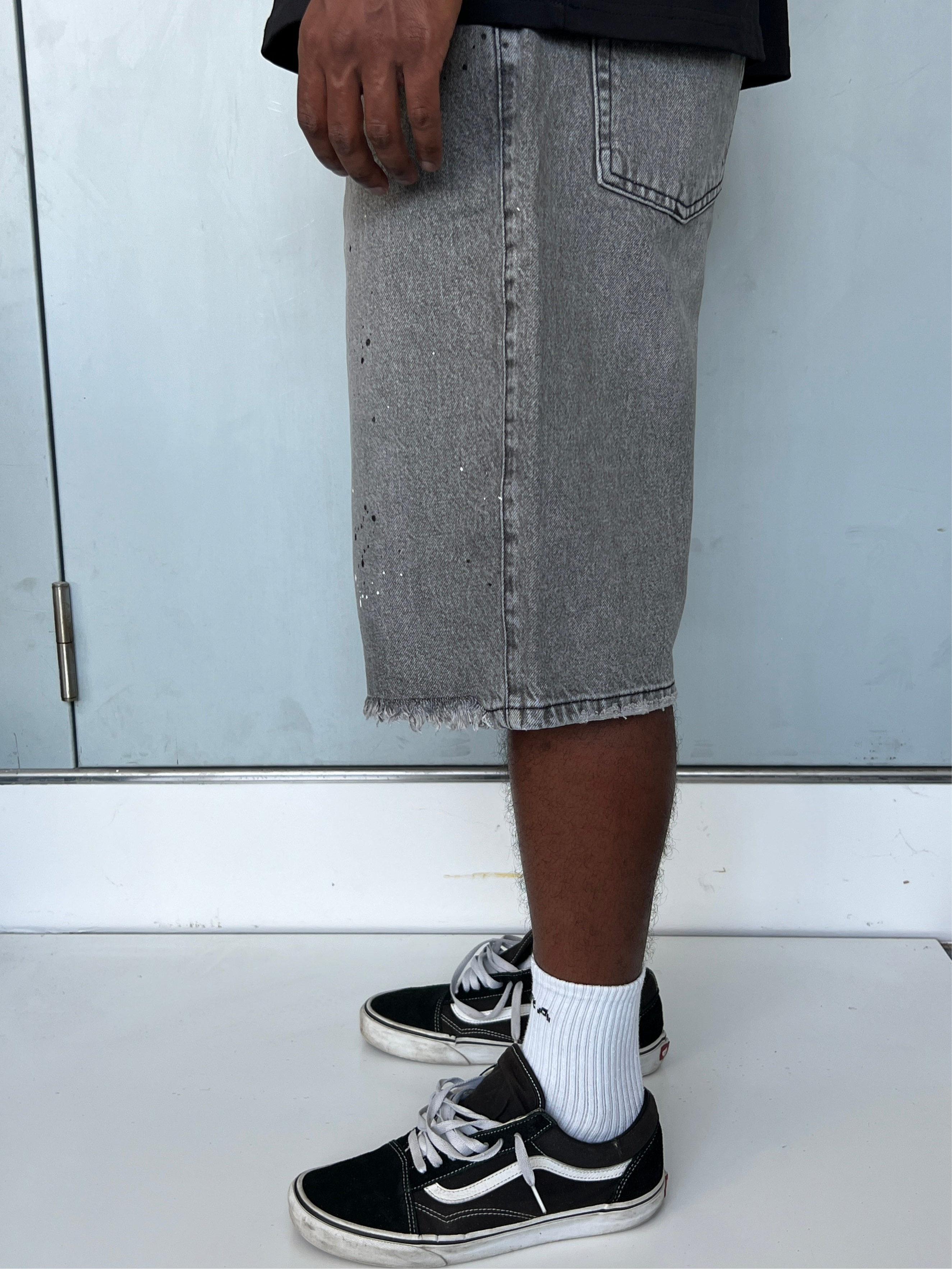 Side view of model wearing Gabriel Abera Splattered Denim Jorts, cropped at waist