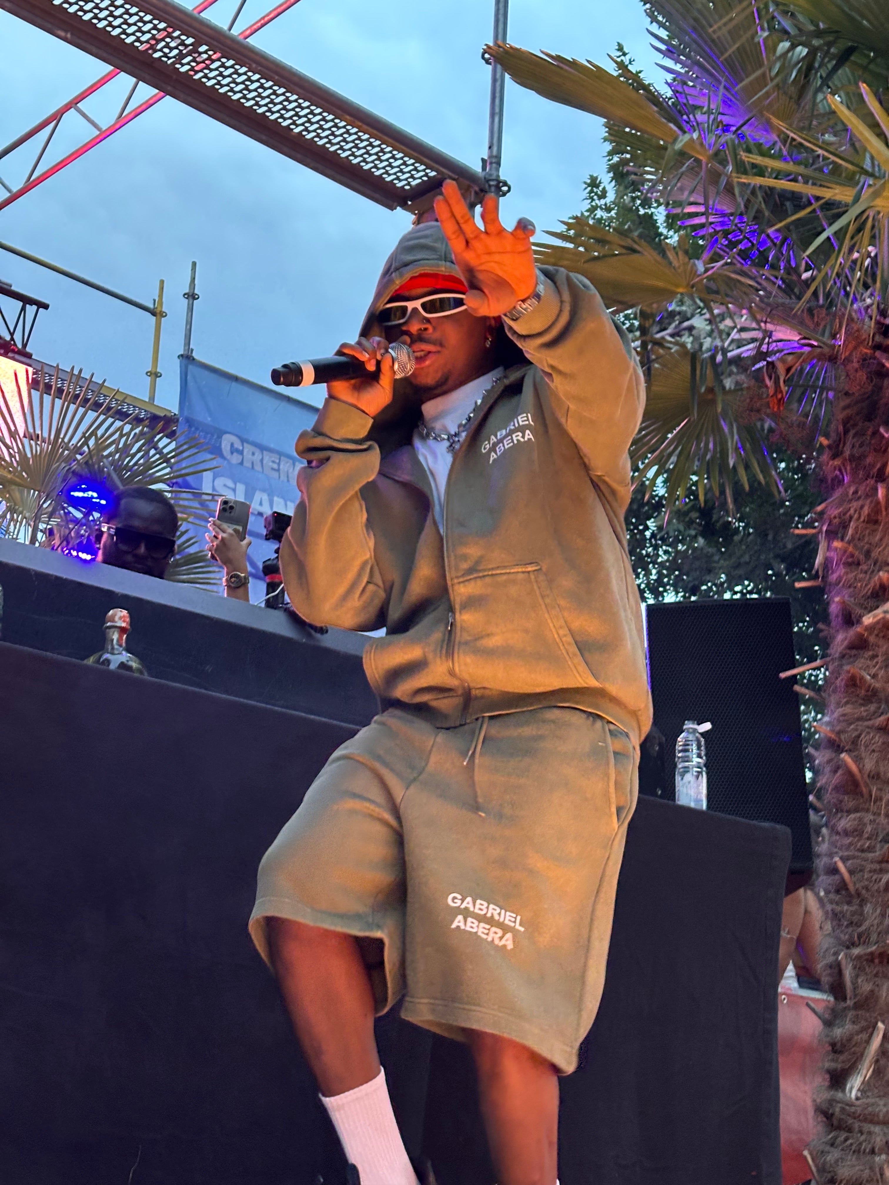 Oxlade performt in Mannheim im Gabriel Abera Look – Vintage Shorts, Zipper und Basic Puff Tee. Ein Auftritt, der Afrobeats mit mutigem Streetstyle verbindet. #ExpressYourself