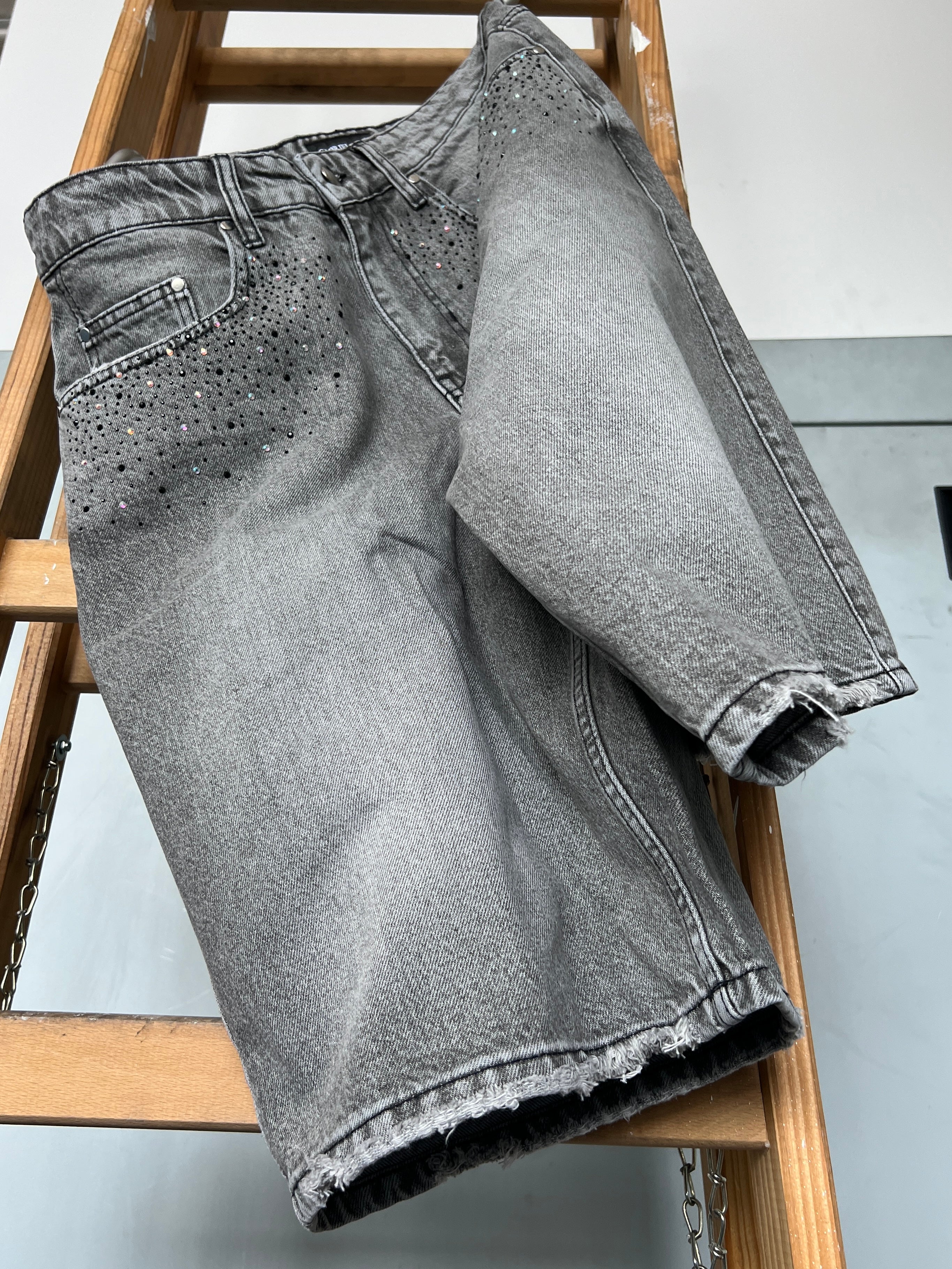 Gabriel Abera Rhinestones Denim Jorts draped over ladder, washed grey with rhinestone detailing