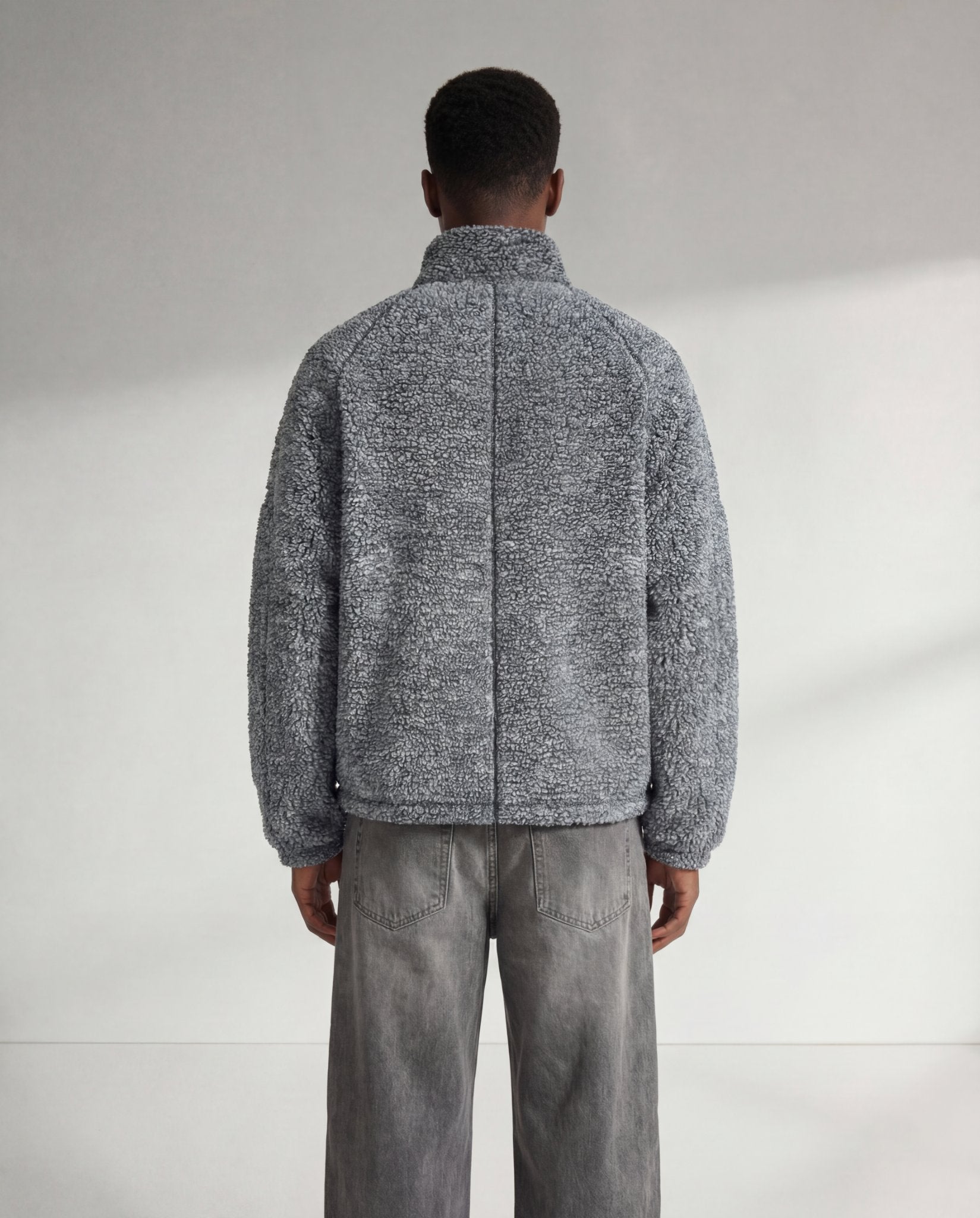 Rückansicht der grauen GABRIEL ABERA Fleecejacke auf männlichem Model, entspannter Schnitt und gleichmäßige Fleece-Struktur.