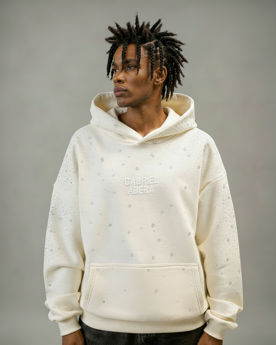Männliches Model trägt GABRIEL ABERA Rhinestone Hoodie in Cream White – Frontansicht mit handgesetzten Rhinestones, Oversized Premium Streetwear