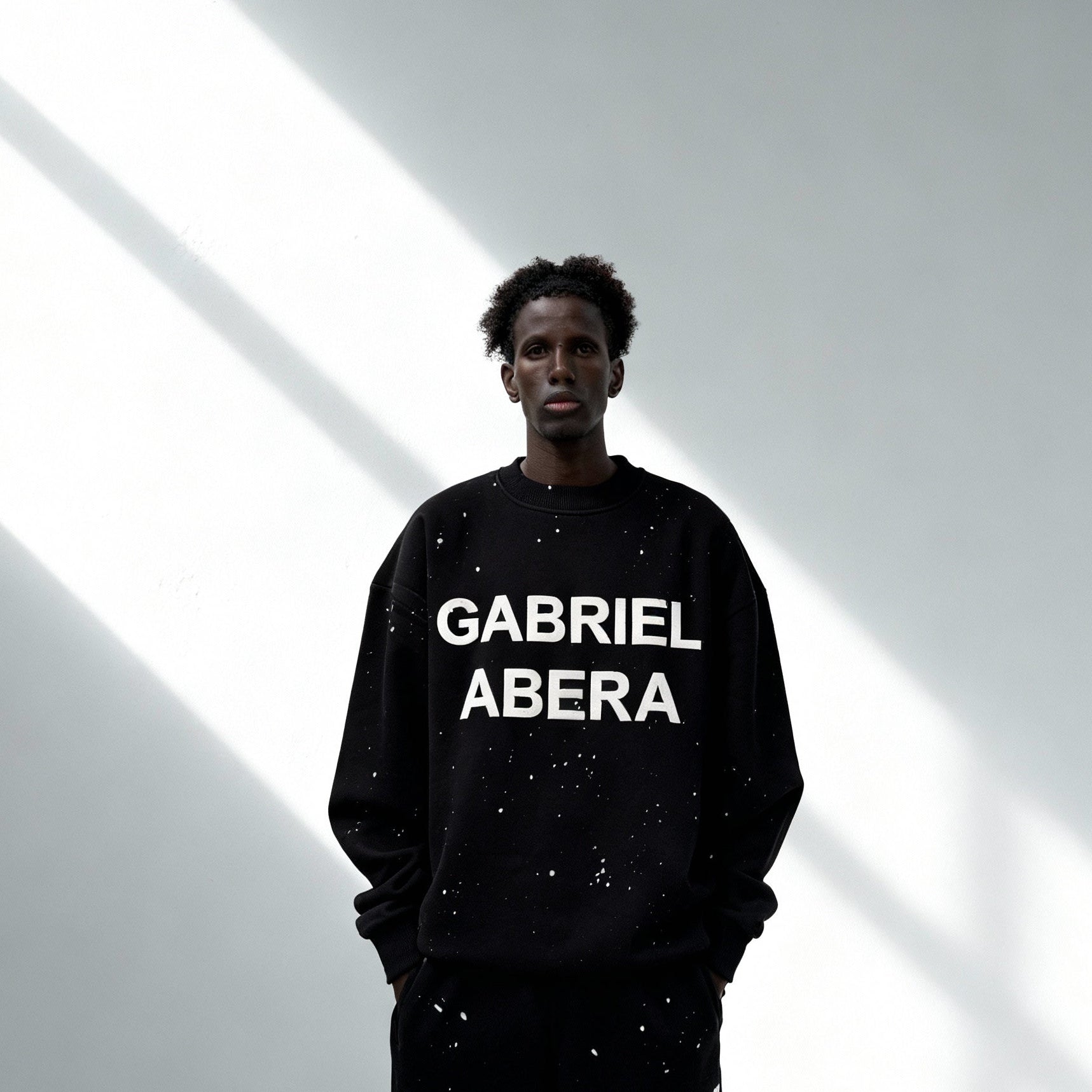 Model trägt GABRIEL ABERA Splattered Puff Sweater Black/White – Vorderansicht im Streetwear Style mit Oversized Schnitt.
