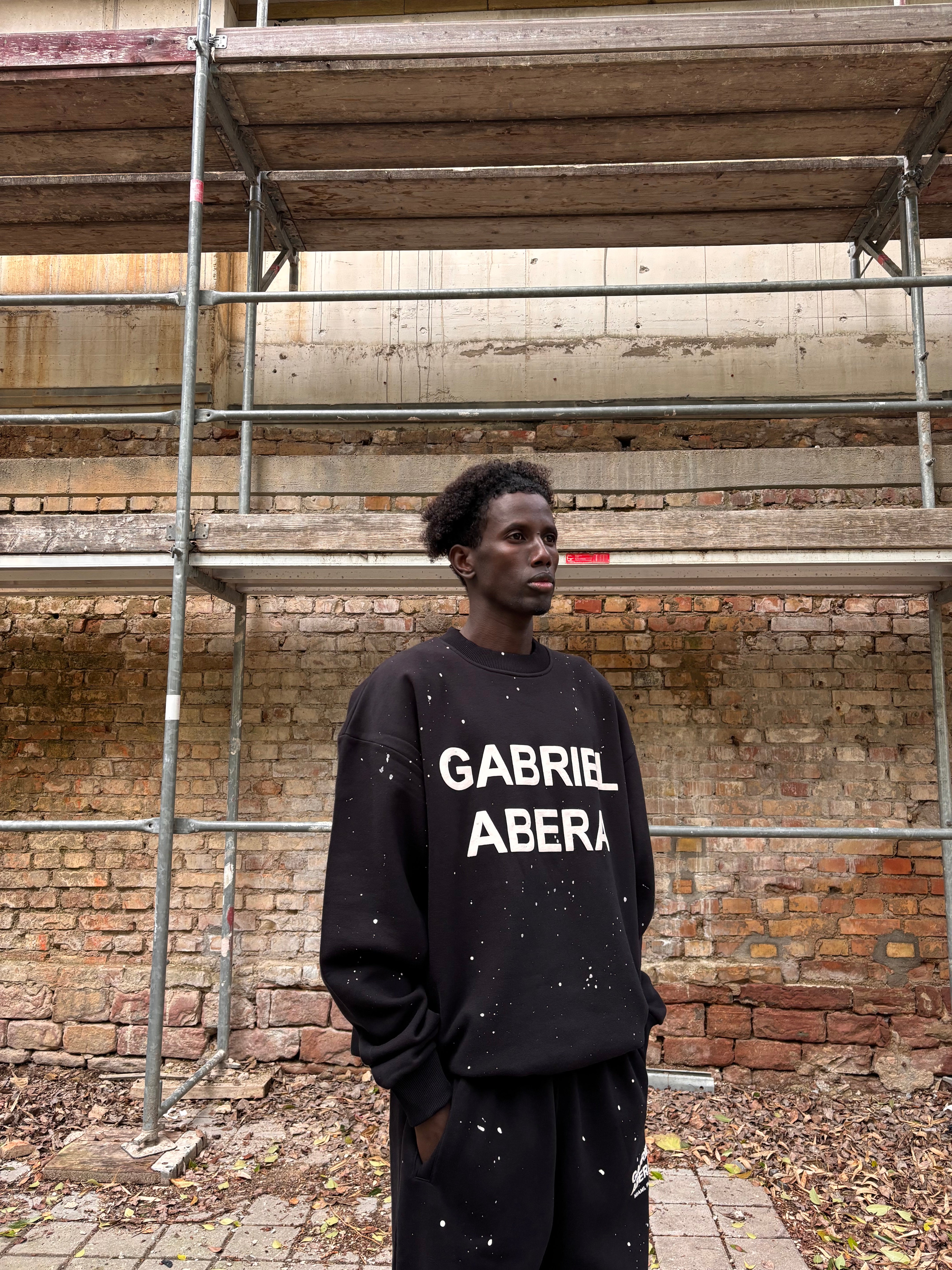 Seitenansicht: Model trägt das GABRIEL ABERA Set aus Splattered Puff Sweater und Pants – Streetwear Look mit lockerer Silhouette und Splatter-Design.