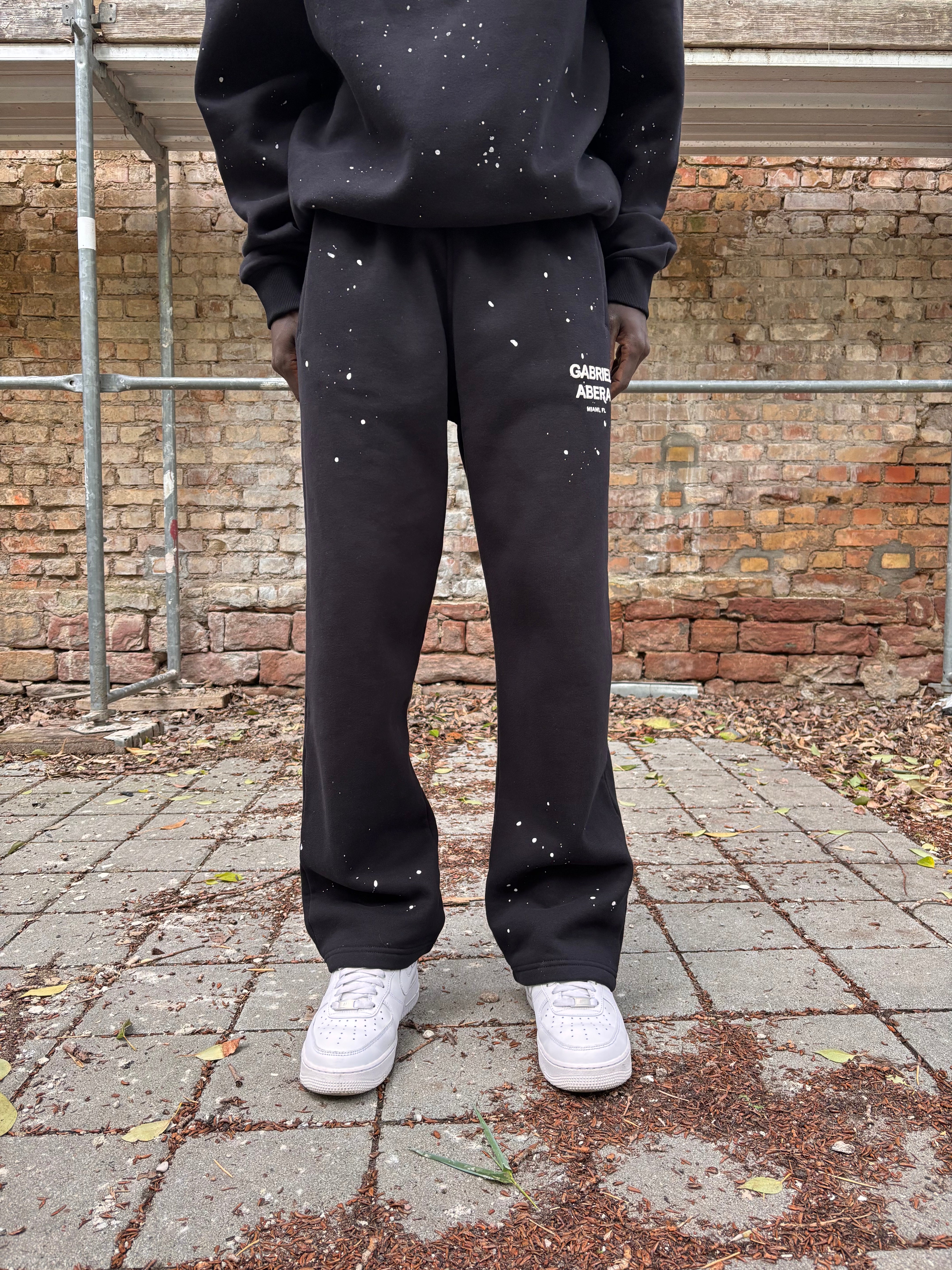 Model trägt GABRIEL ABERA Splattered Sweatpants Black/White – vorneansicht im vollständigen Outfit Look.