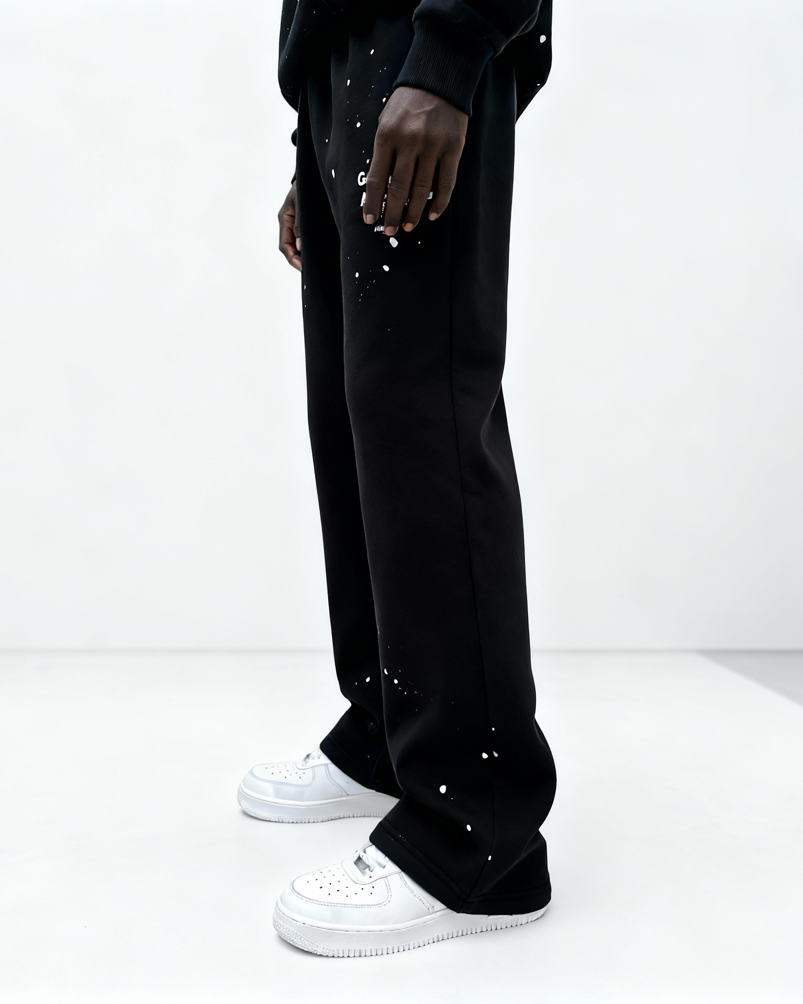 Seitenansicht: Model trägt GABRIEL ABERA Splattered Sweatpants Black/White im Set mit passenden Oberteilen, Oversized Fit mit Splatter-Effekt.