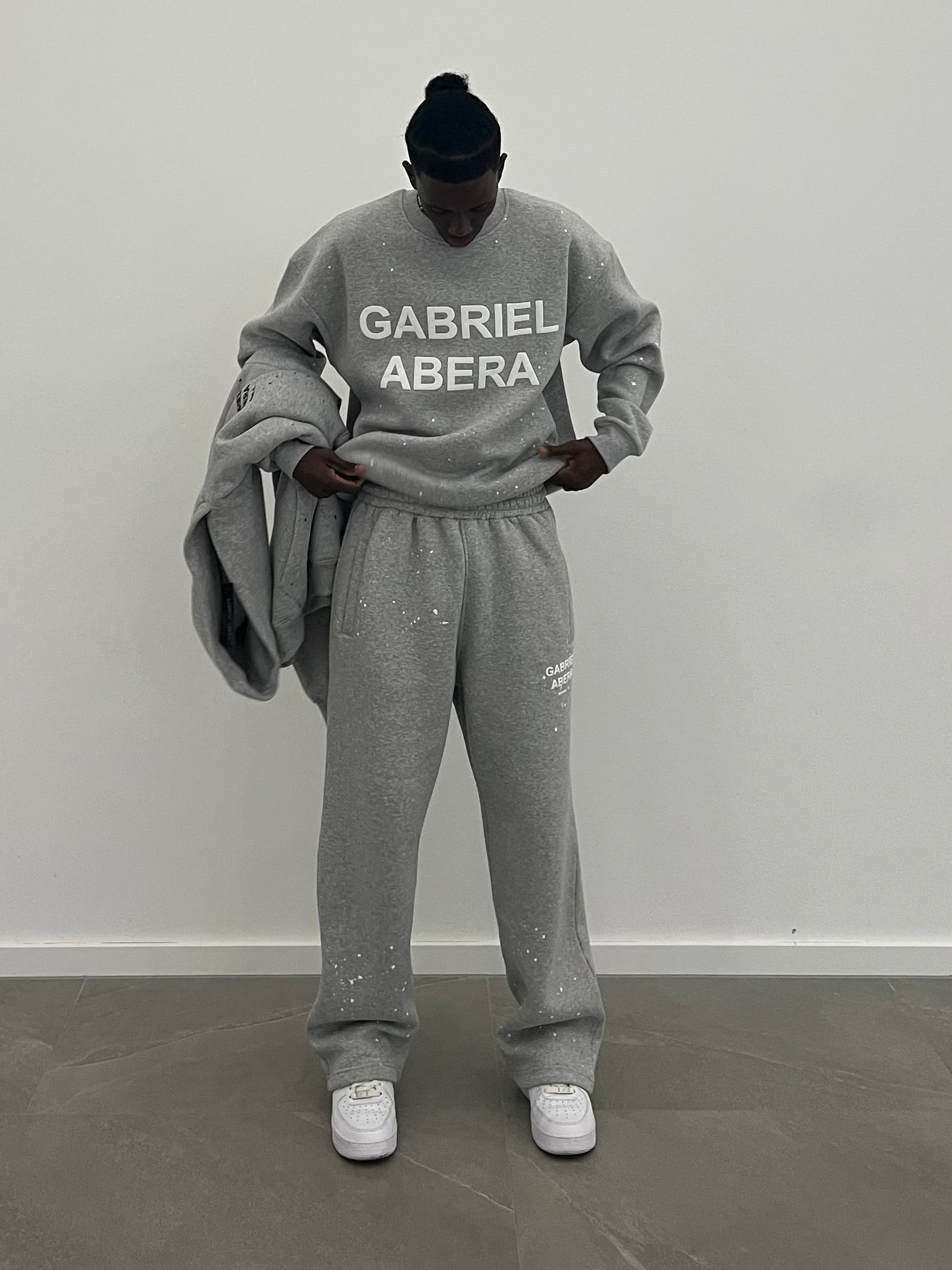 Model trägt die grey Splattered Sweatpants and matching Hoody mit artistic Splatter-Design, Baggy Fit und auffälligem white Puff Print
