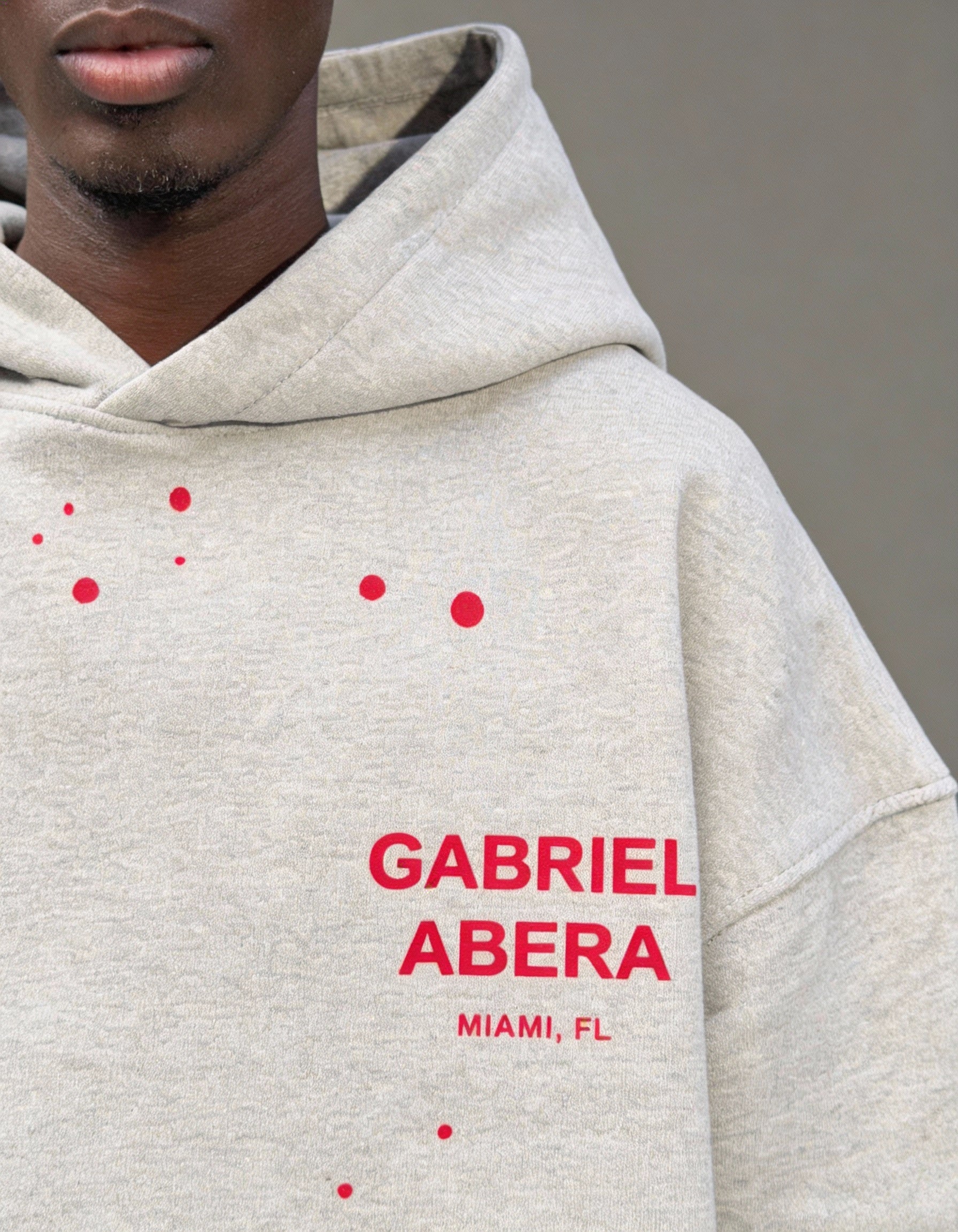 Nahaufnahme des GABRIEL ABERA splattered Hoodie in grey with red – handgesetzte Rhinestones, hochwertige Stoffstruktur und Premium Verarbeitung.