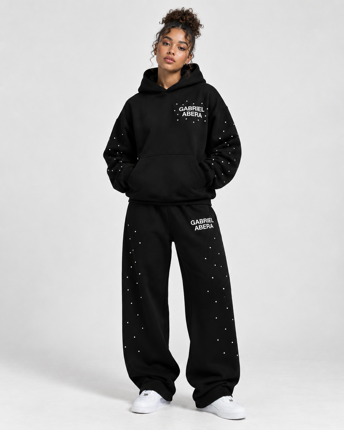 Ganzkörperaufnahme des schwarzen GABRIEL ABERA Rhinestone Astral Hoodies als moderner unisex Streetwear Look