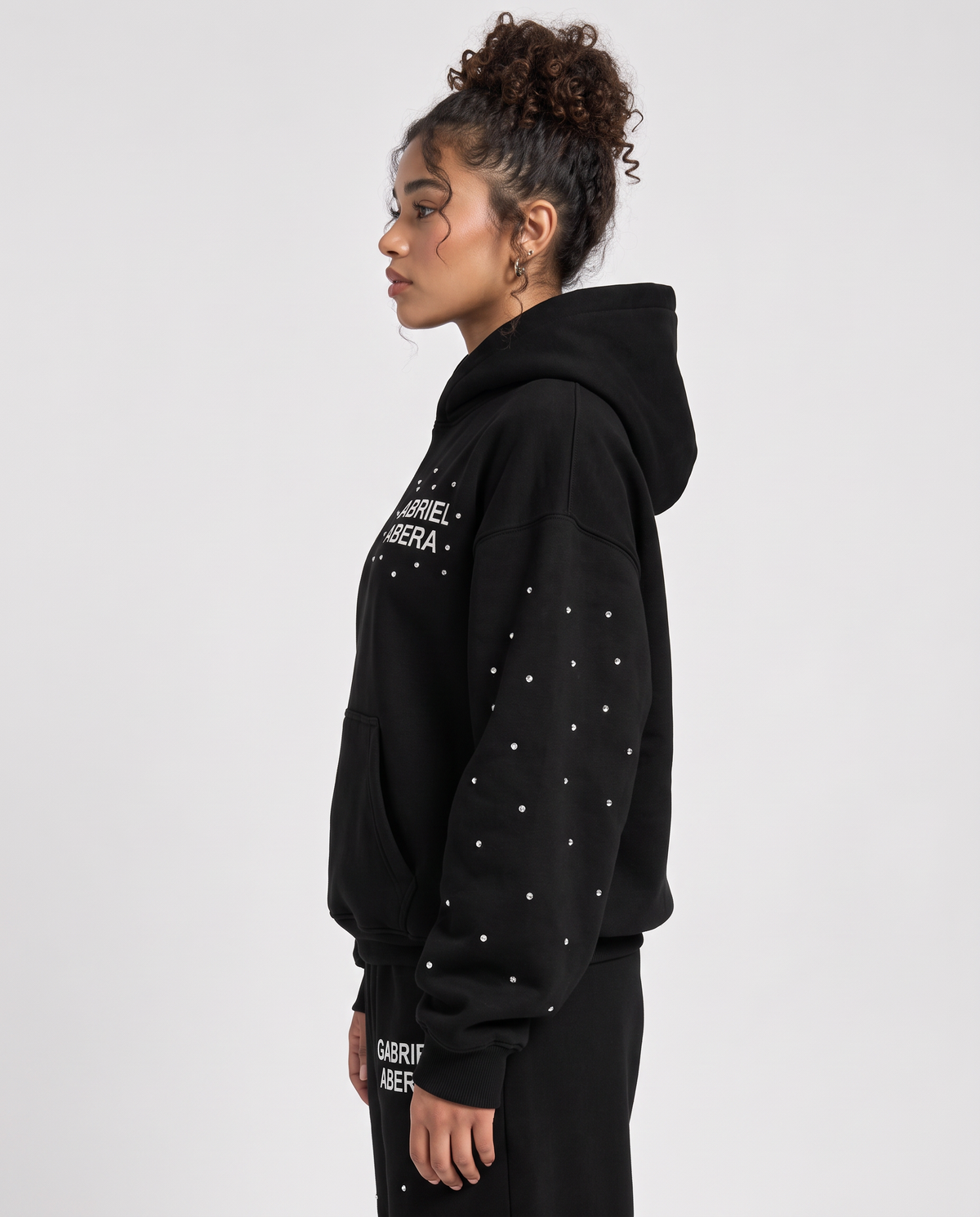 Seitliche Ansicht des schwarzen GABRIEL ABERA Rhinestone Astral Hoodies für sie und ihn im Oversized Streetwear