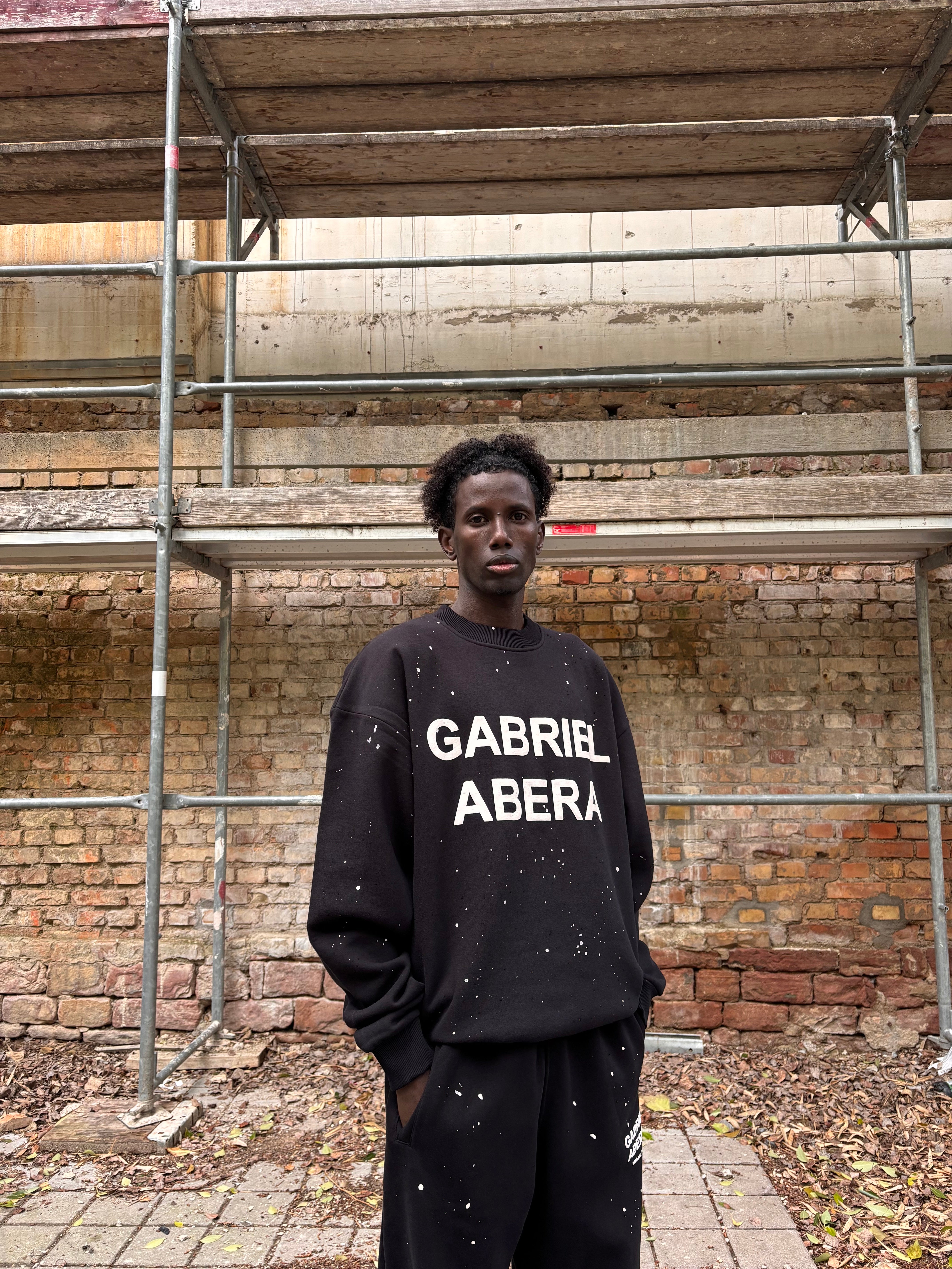 Seitenansicht des GABRIEL ABERA Splattered Puff Sweater Black/White – Oversized Fit mit charakteristischen Farbspritzern.