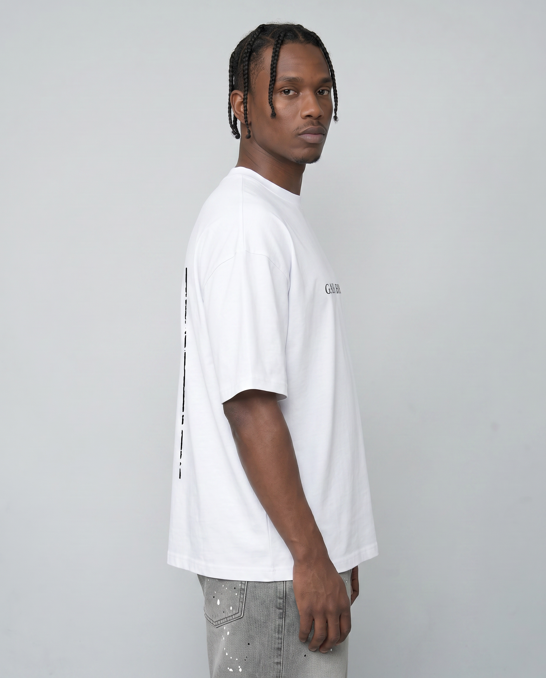 Side view male model wearing cream white oversized t-shirt showing dropped shoulder and loose silhouette