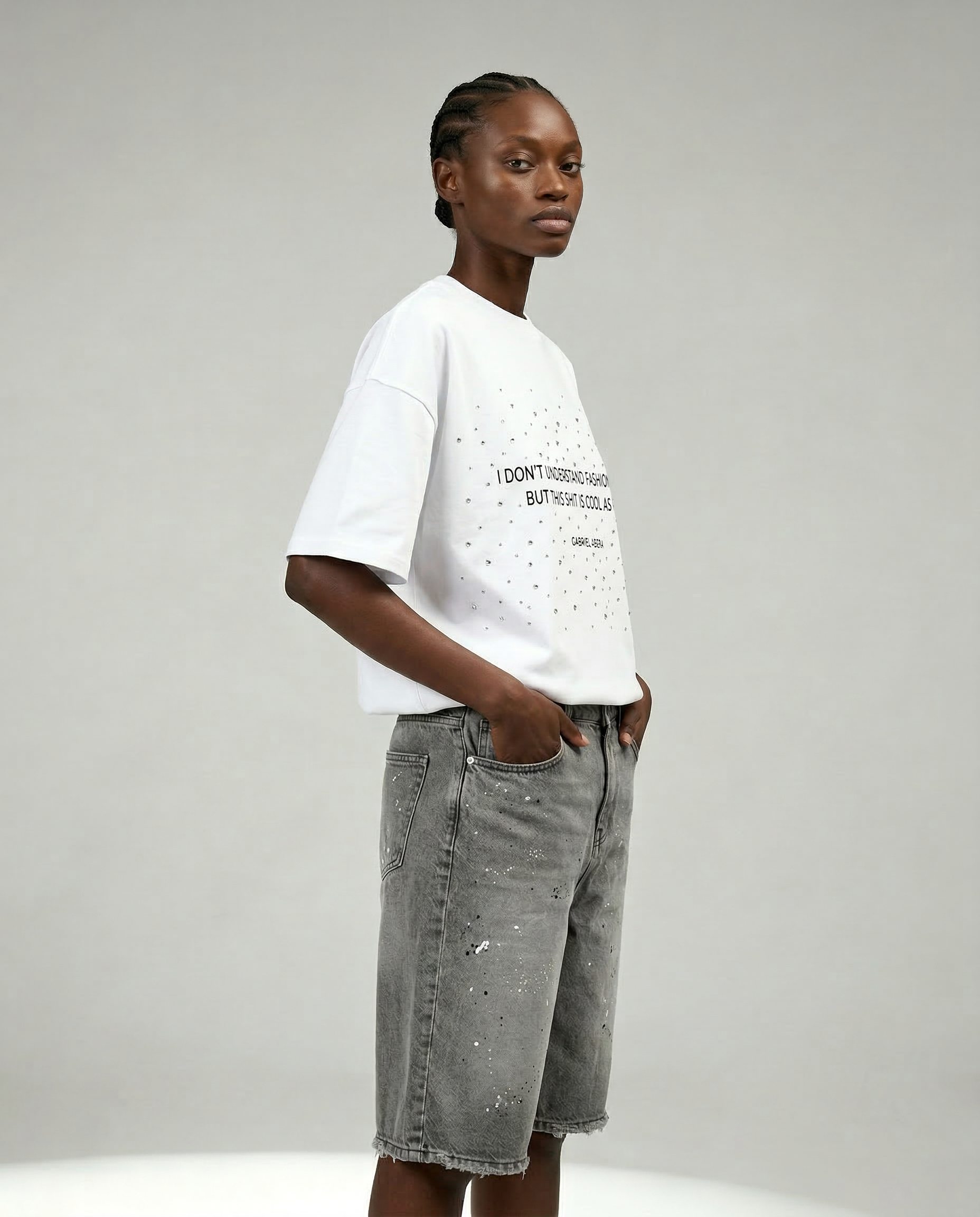 Side view of female model wearing Gabriel Abera Paint Splattered Denim Shorts with paint splatter, cropped at waist
