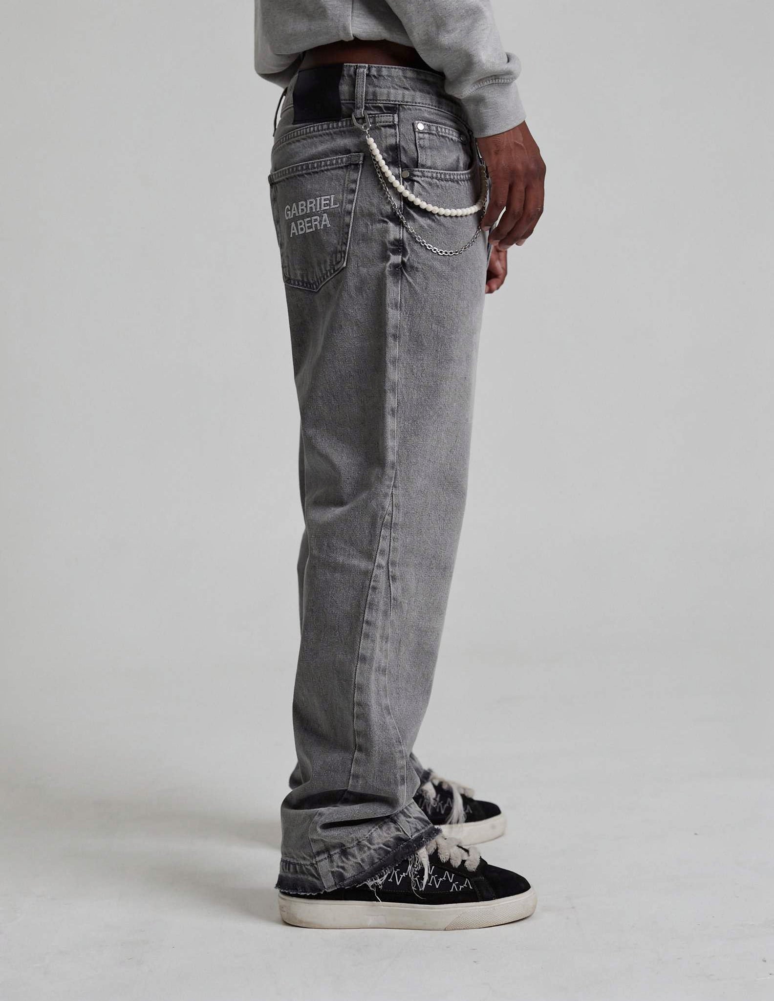 Side view of grey rhinestone denim jeans by GABRIEL ABERA showing loose streetwear fit and stonewashed grey fabric.