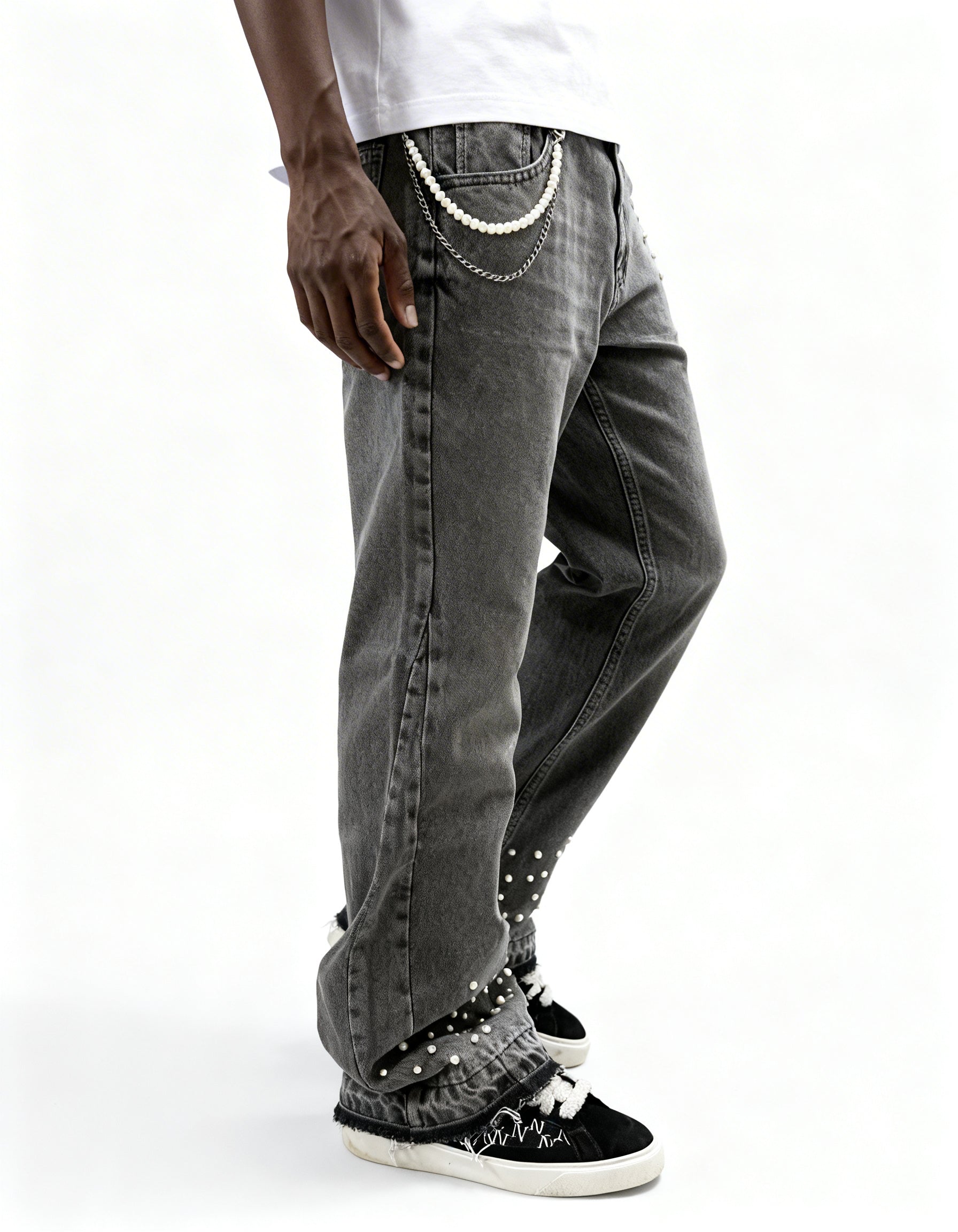 Side view of grey pearl denim jeans with chain by GABRIEL ABERA showing loose fit cut and rhinestone embellishments on pocket and hem.