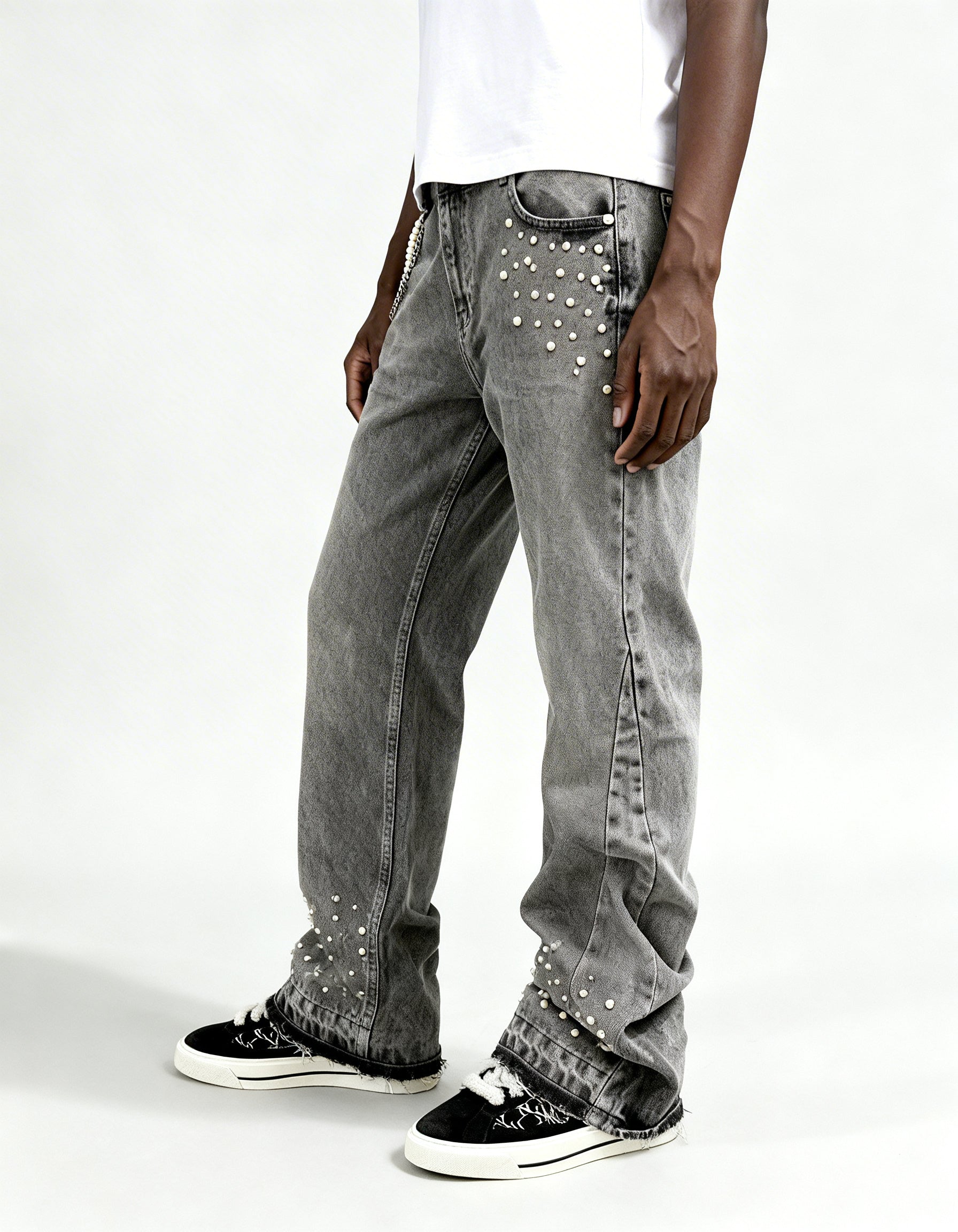 Side view of grey rhinestone denim jeans by GABRIEL ABERA showing loose fit cut and rhinestone embellishments on pocket and hem.