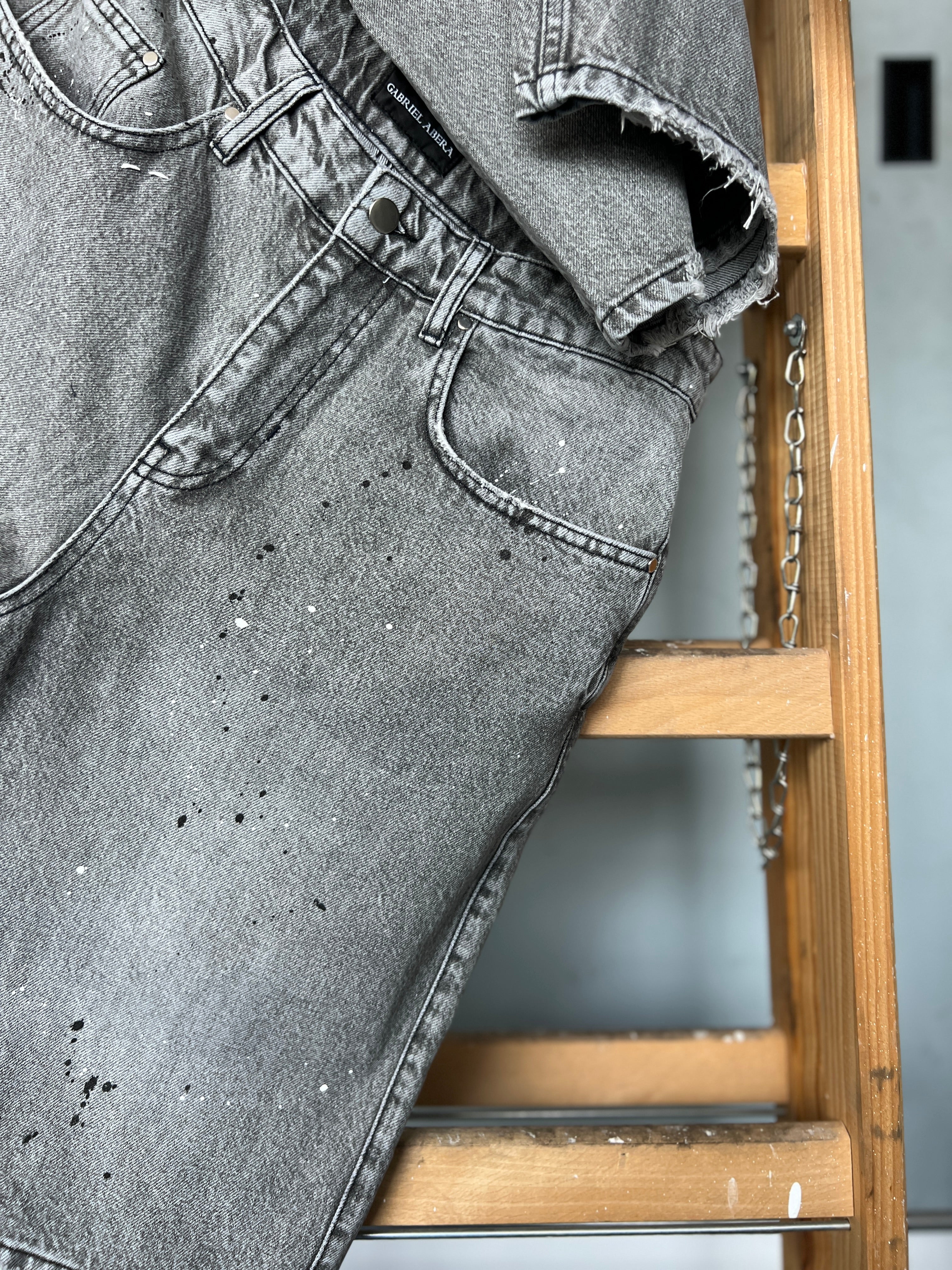 Close-up of paint splatter detail on Gabriel Abera Splattered Denim Jorts hanging on ladder
