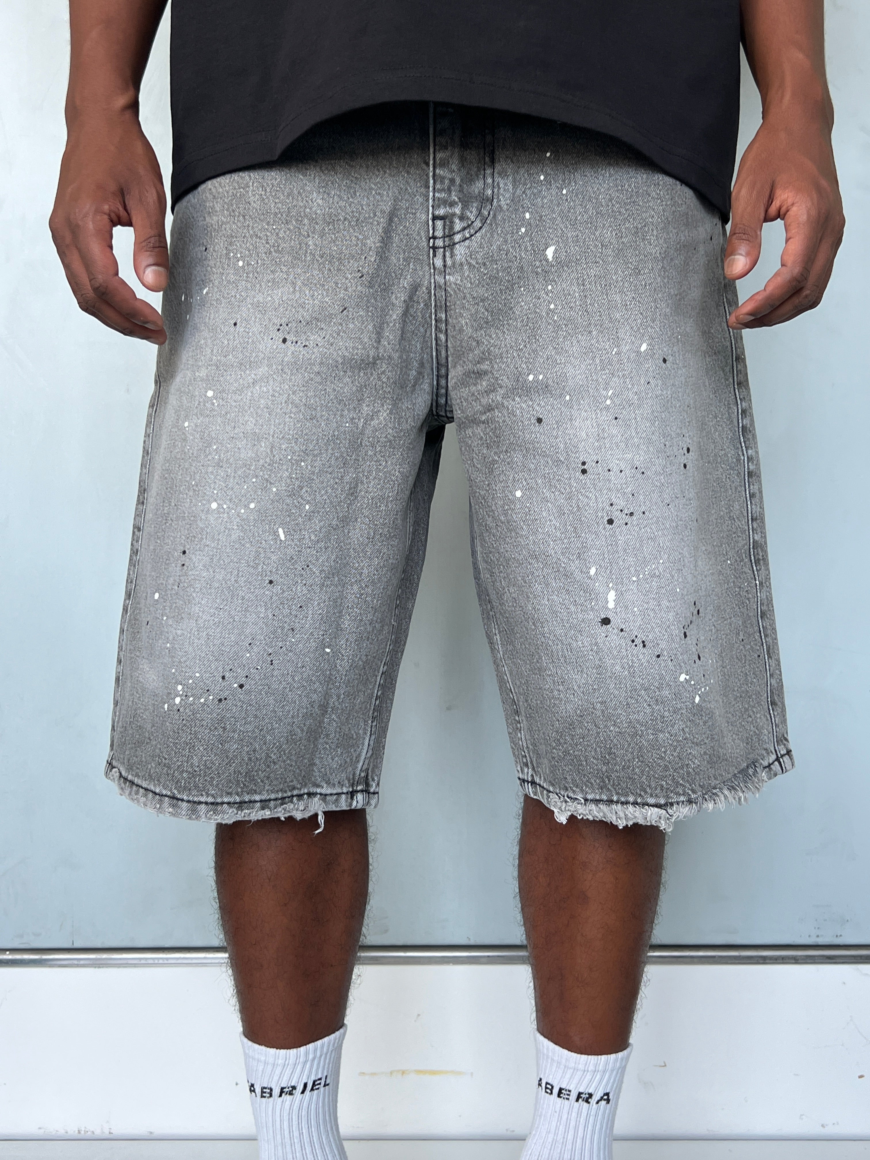 Front view of model wearing Gabriel Abera Splattered Denim Jorts, cropped at waist