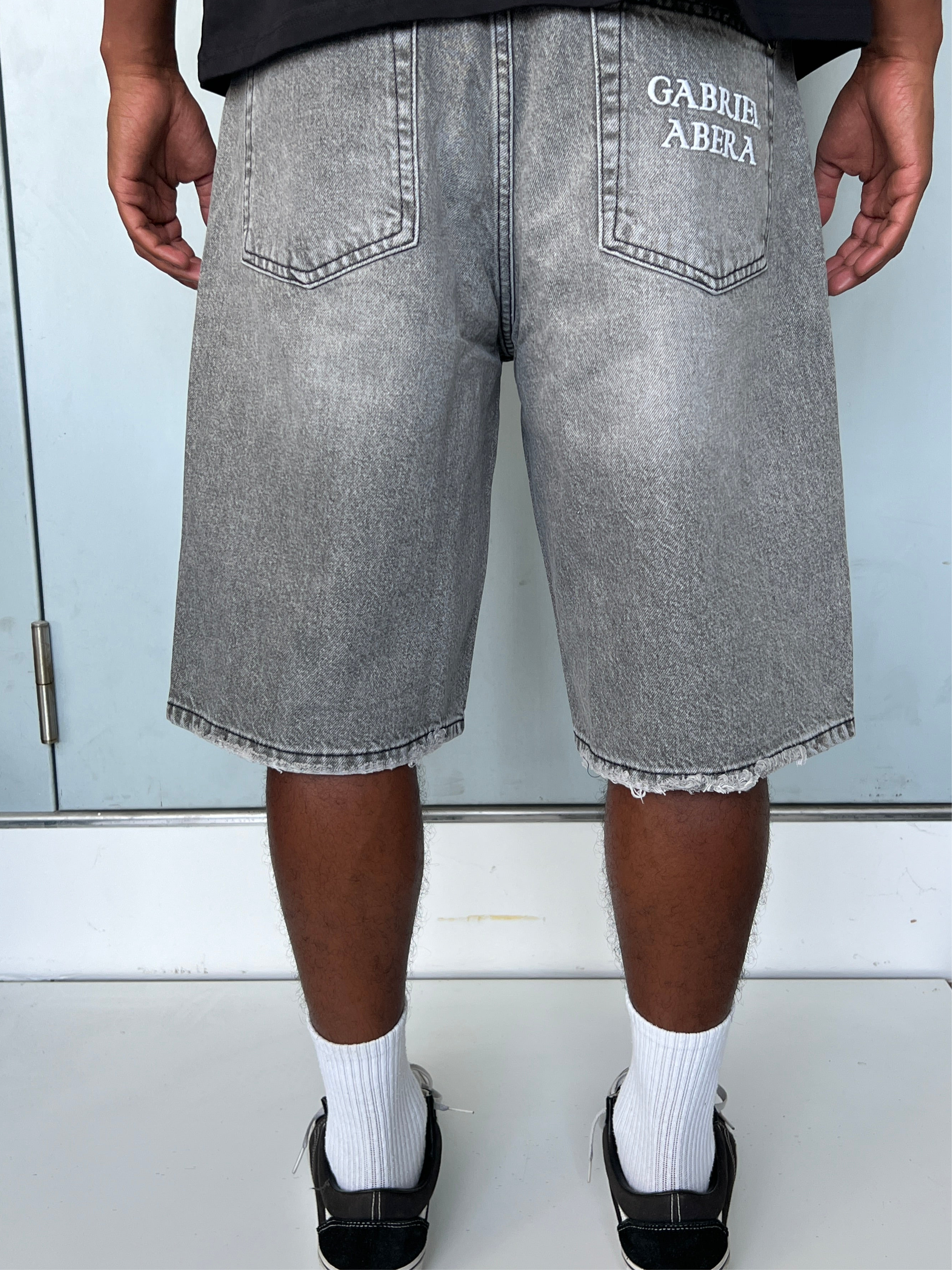 Back view of model wearing Gabriel Abera Splattered Denim Jorts, cropped at waist