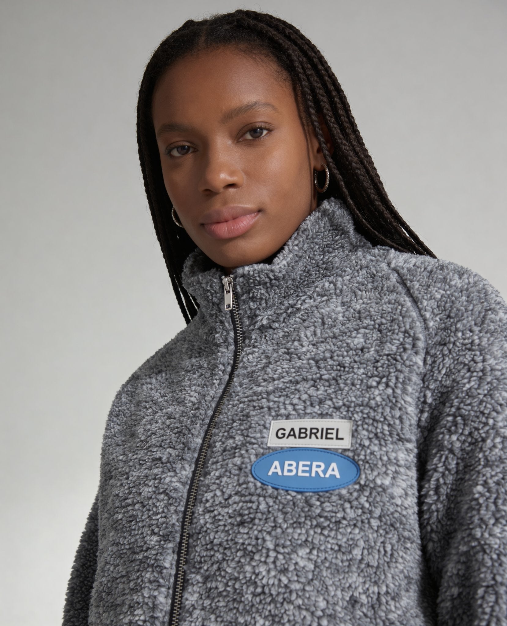 Detailaufnahme der grauen GABRIEL ABERA Fleecejacke, Fleece-Struktur und Logo-Patch in Nahaufnahme, hochwertige Verarbeitung sichtbar.