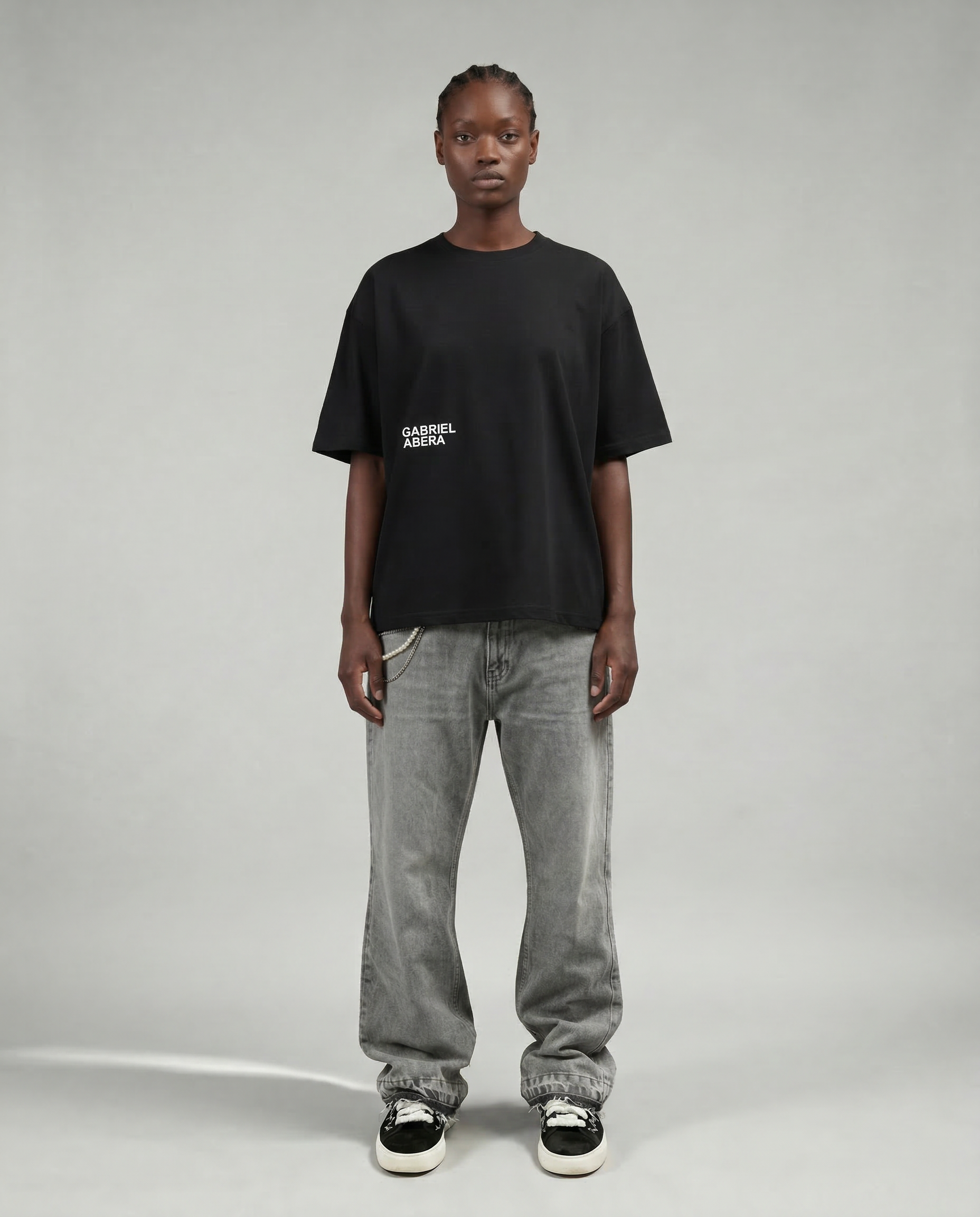 front view of female model wearing ASH FLARE DENIM in WASHED GREY with chains and basic puff print tee by Gabriel Abera permium streetwear.