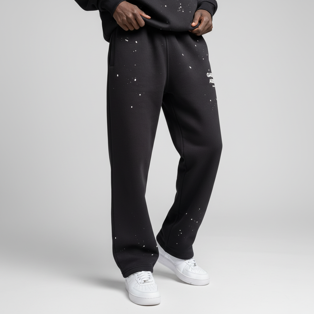 Seitenansicht: Model trägt GABRIEL ABERA Splattered Sweatpants Black/White im Set mit passenden Oberteilen, Oversized Fit mit Splatter-Effekt.