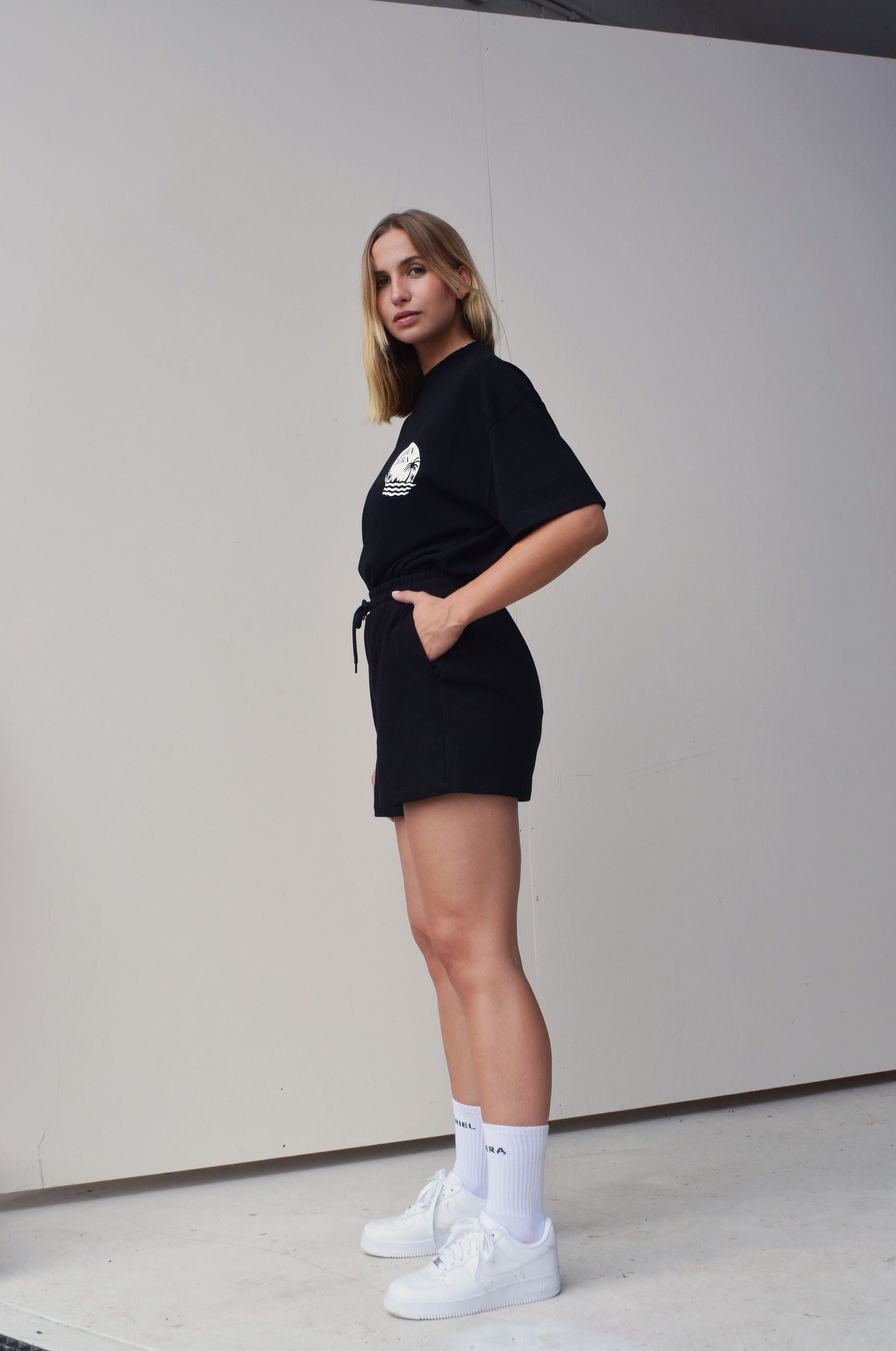 Female model wearing a Black oversize Tshirt with round brand design