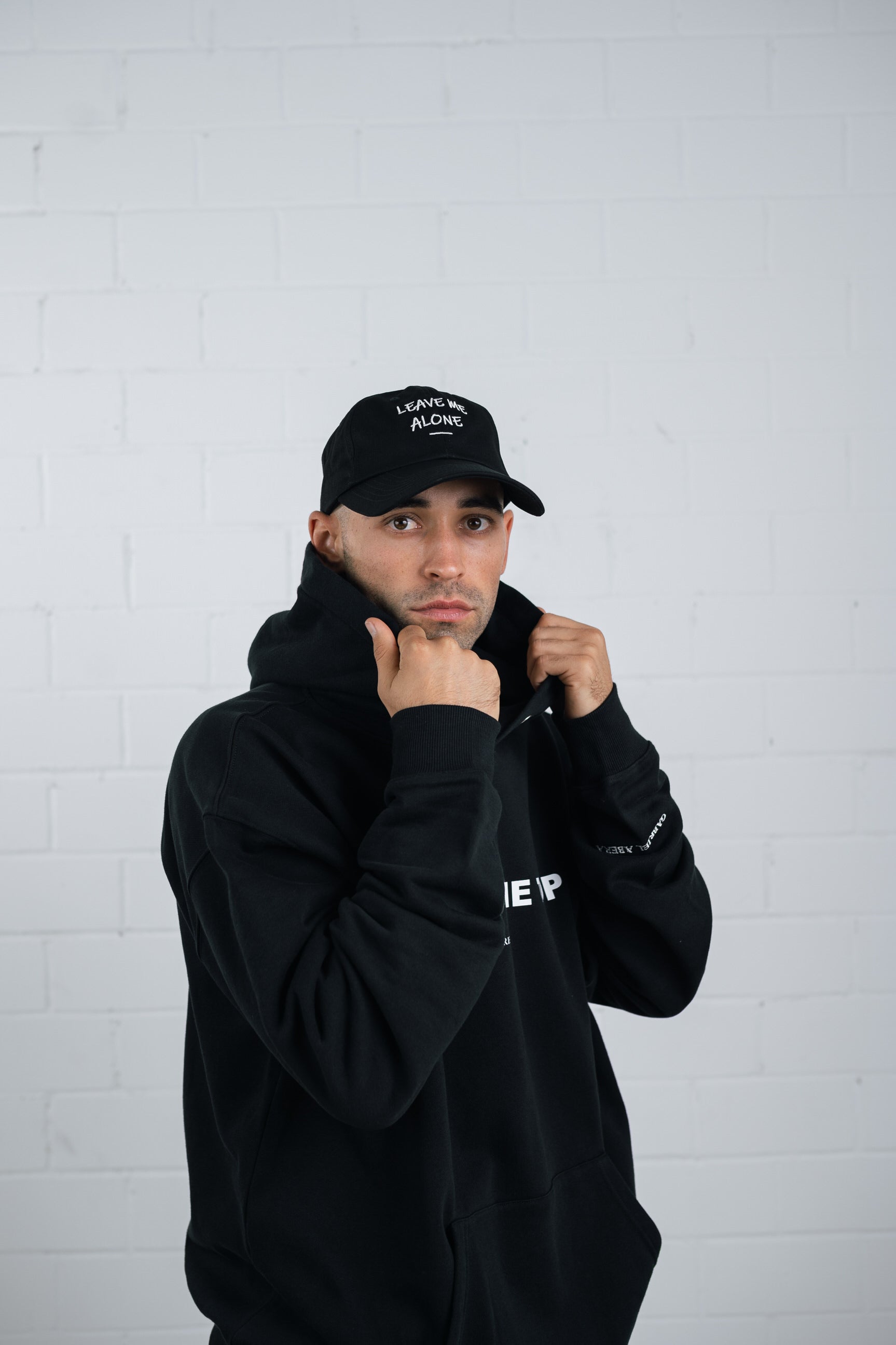Female model wearing a Black cap with white leave me alone embroidery in the front