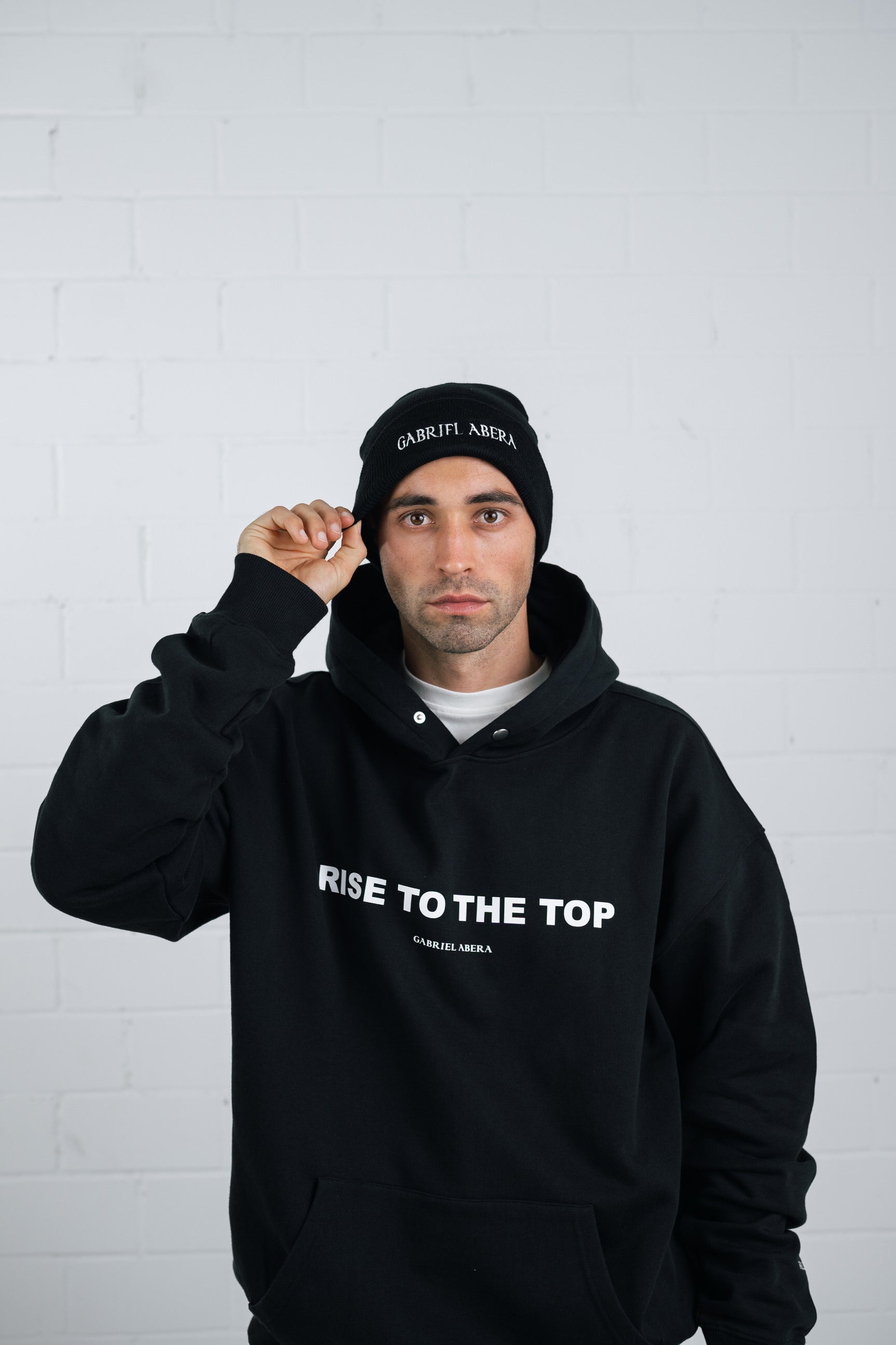 Male model wearing a Black beanie with brand name embroidery