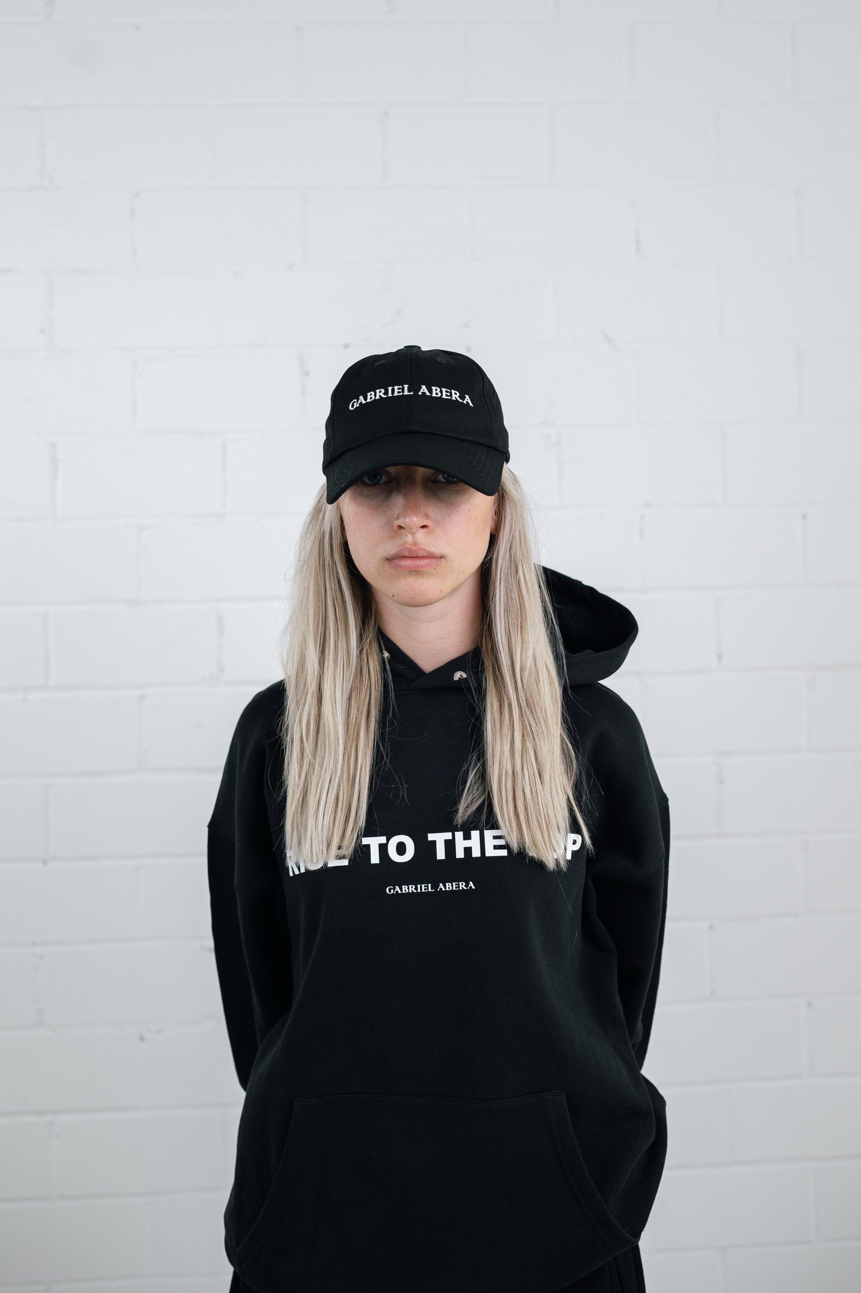 Female model wearing a Black cap with brand name embroidery