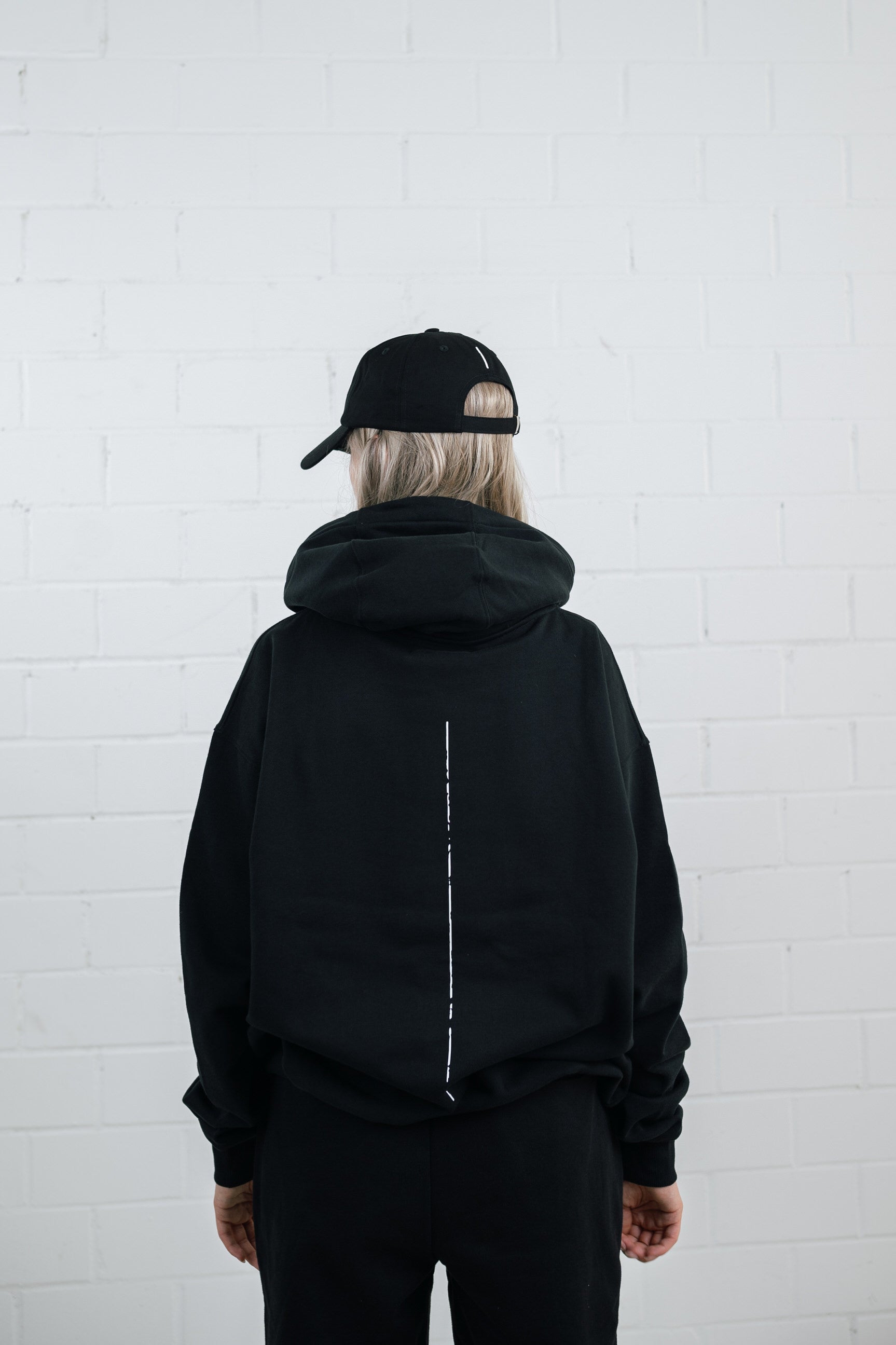 Female model wearing a Black cap with brand name embroidery