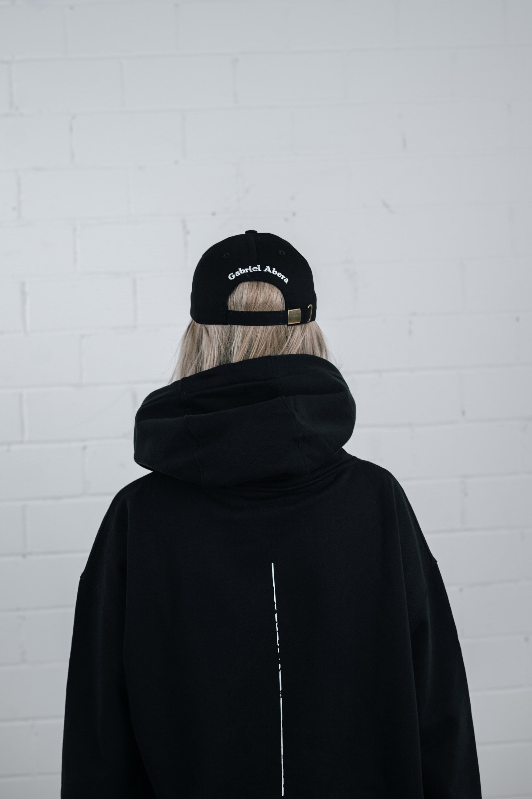 Male model wearing a Black cap with white brand name embroidery