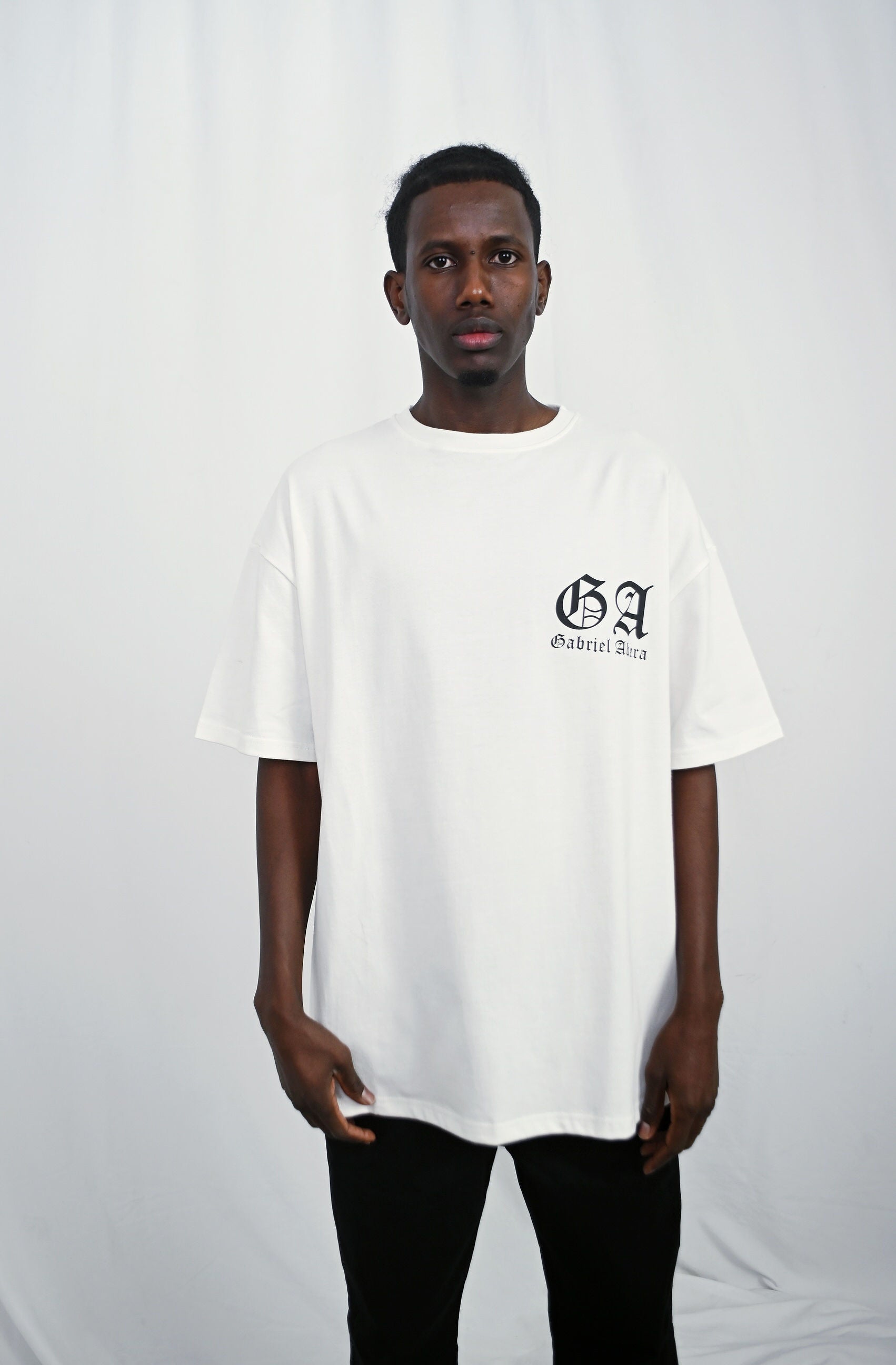 Male model wearing a white oversize Tshirt with brand design on the front