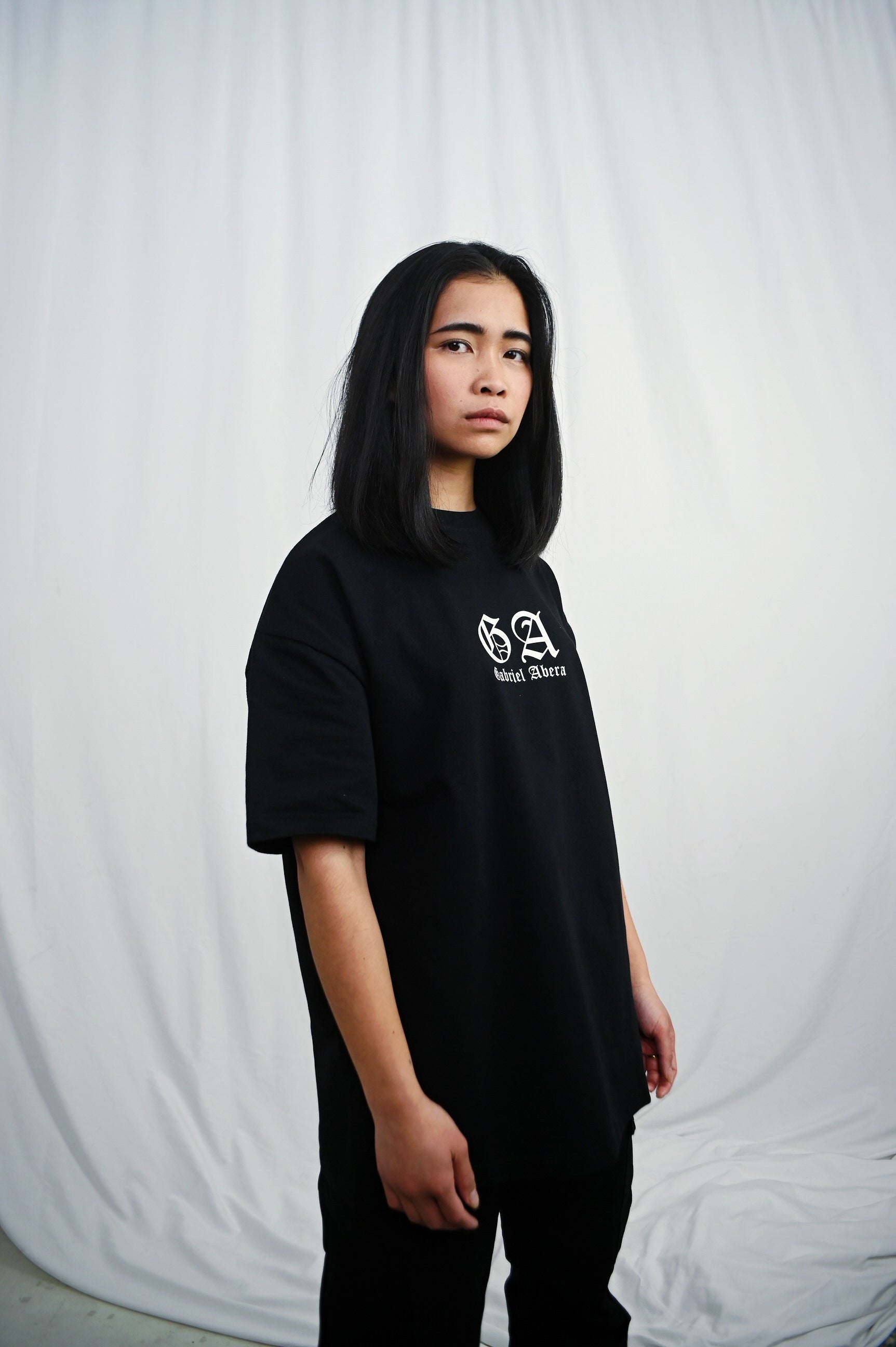 Female model wearing s Black oversize Tshirt with brand design on the front