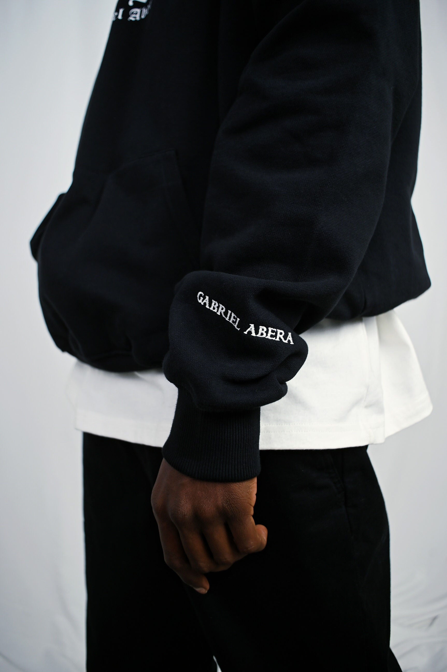 Male model wearing a Black oversize hoodie with white brand design on the sleeve