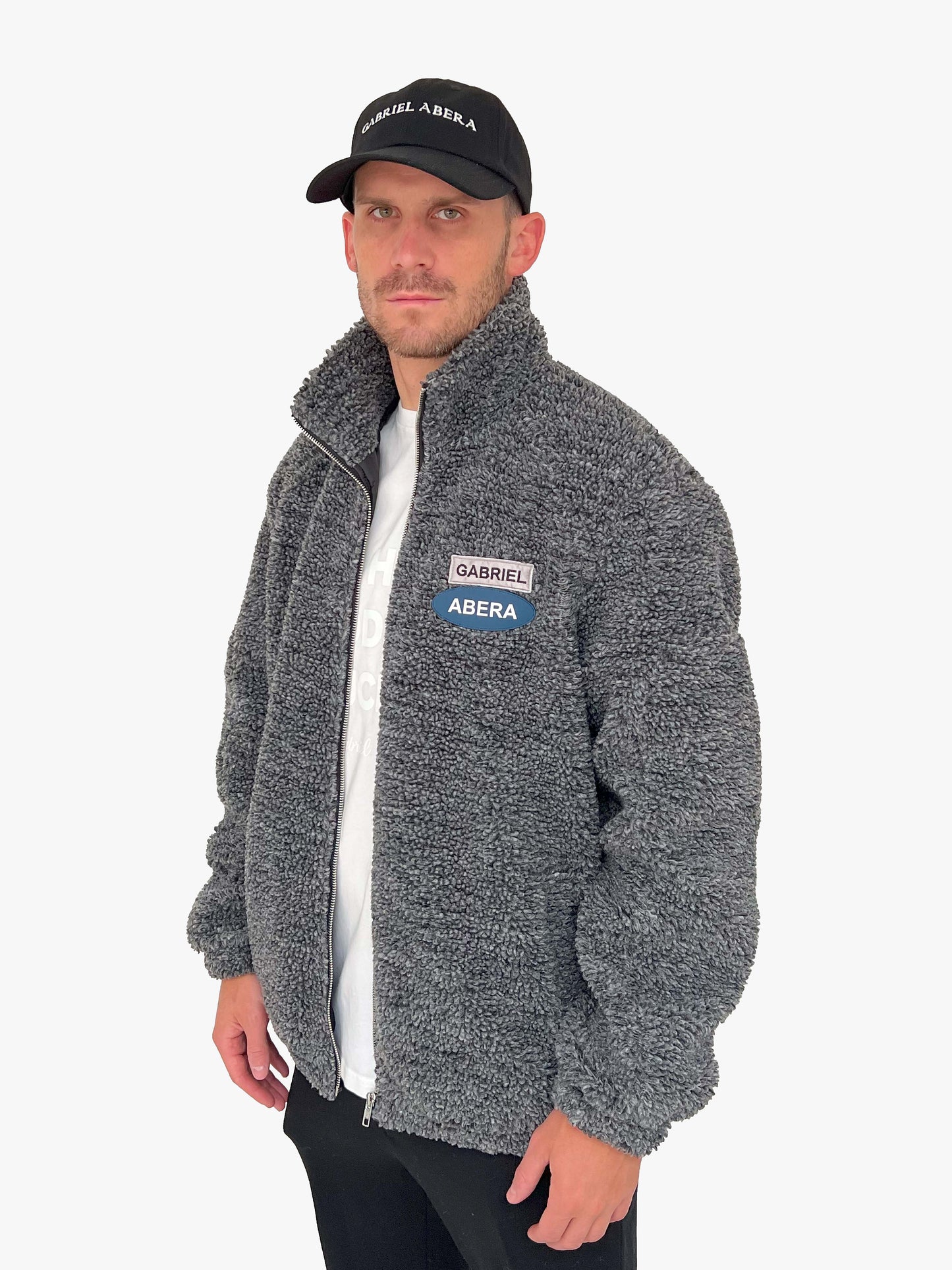 Male model wearing a black fleece jacket with grey and blue brand patches